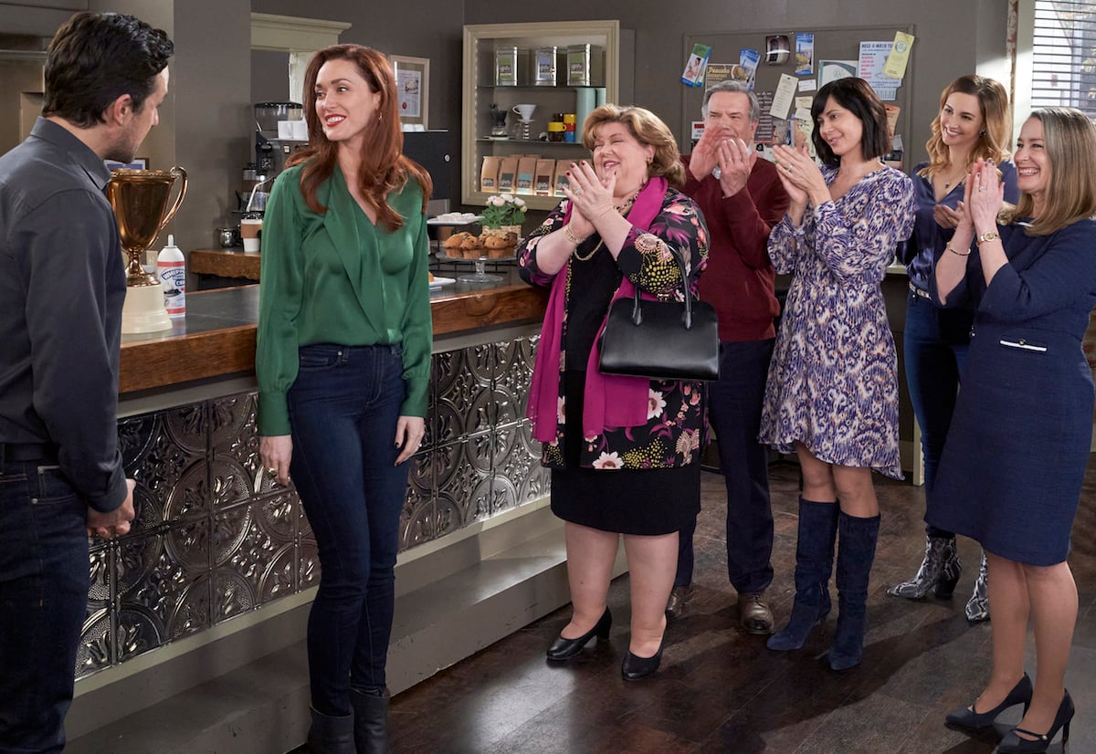 Abigail in a green shirt and jeans standing next to other cast members in episode of 'Good Witch'