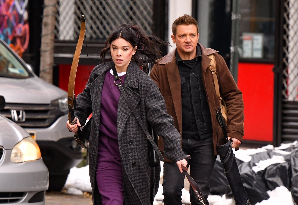 Hailee Steinfeld (L) and Jeremy Renner seen on the set of 'Hawkeye' with Steinfeld holding a bow and a dog leash