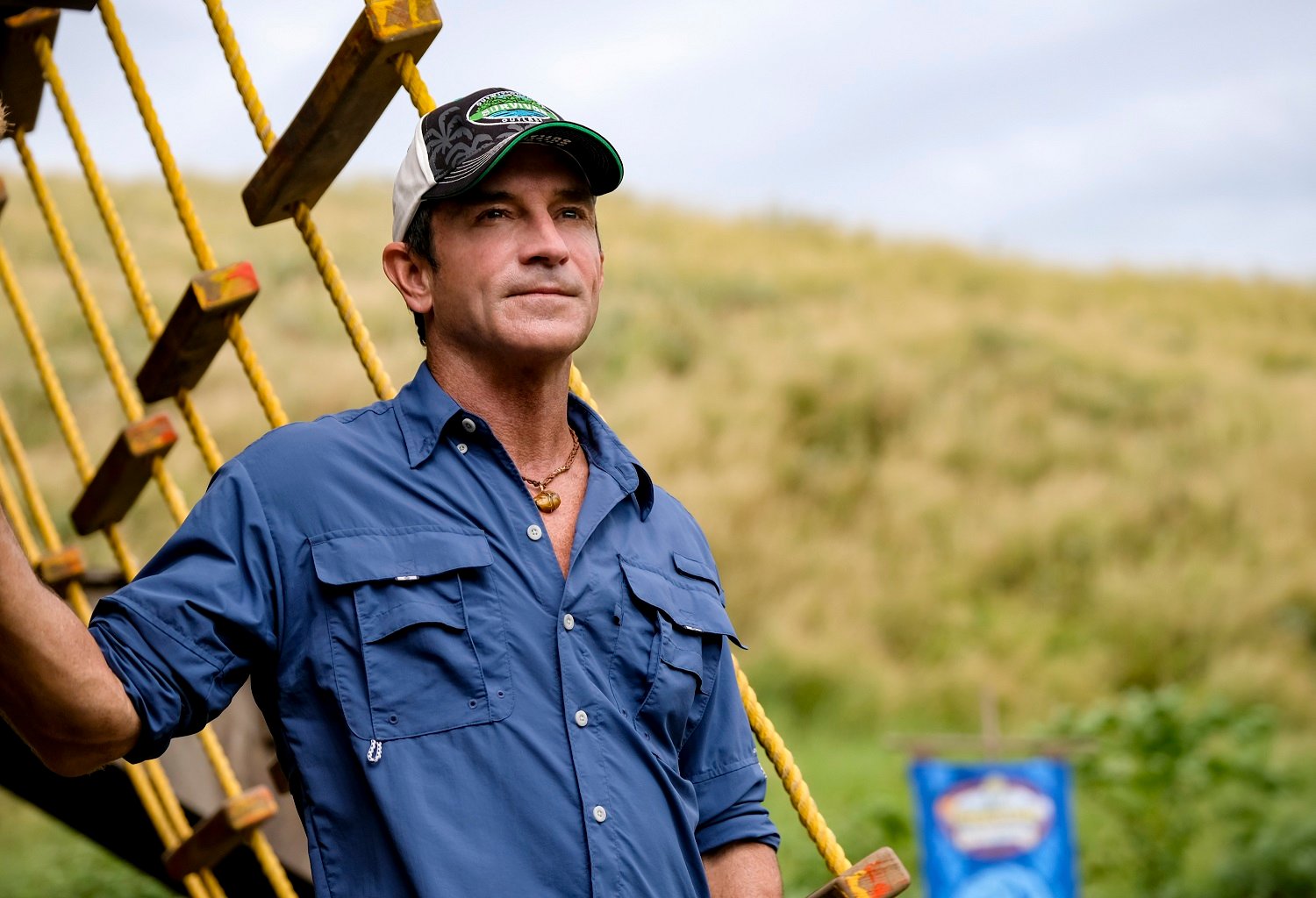 Jeff Probst, host of Survivor 41 wearing a blue button down, standing on a boat, looking into the distance