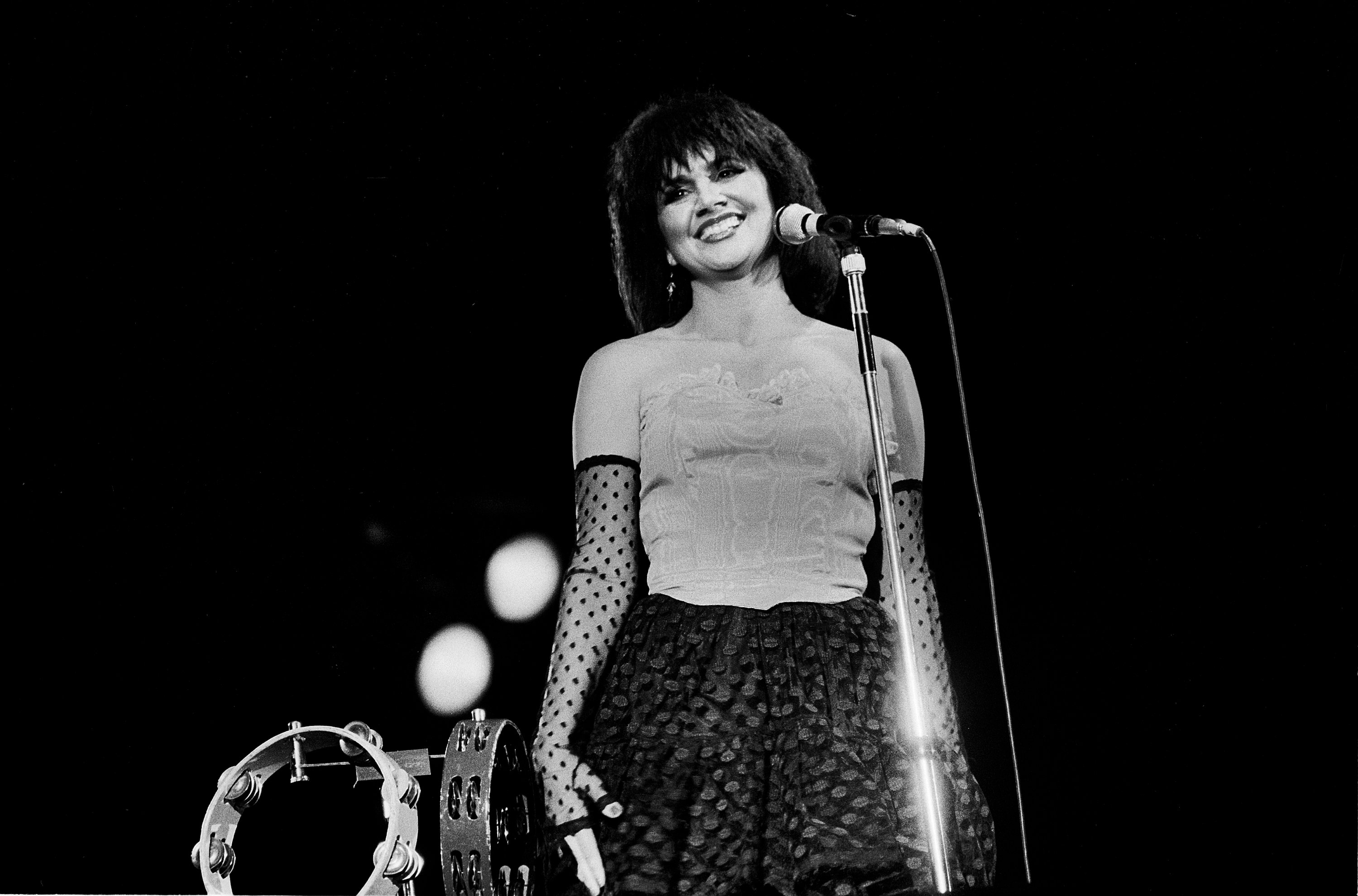 Linda Ronstadt smiling in front of a microphone