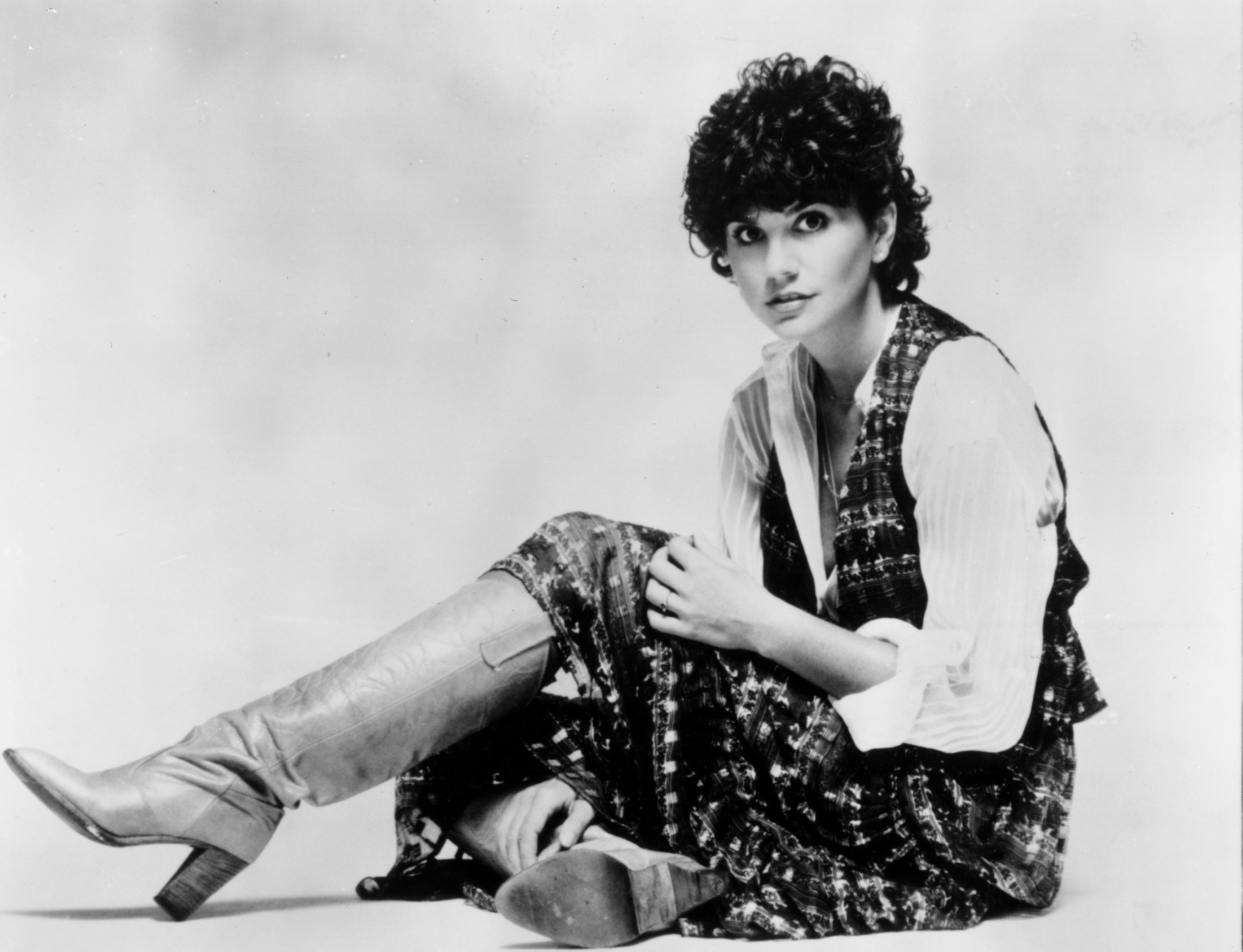 Linda Ronstadt wearing boots and sitting on a floor