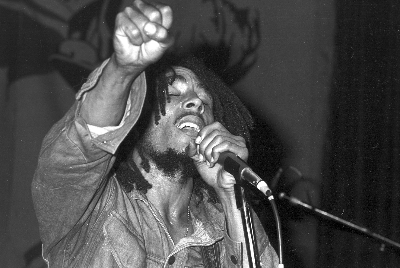 Bob Marley sings, eyes closed, fist raised, while holding a microphone in 1975.