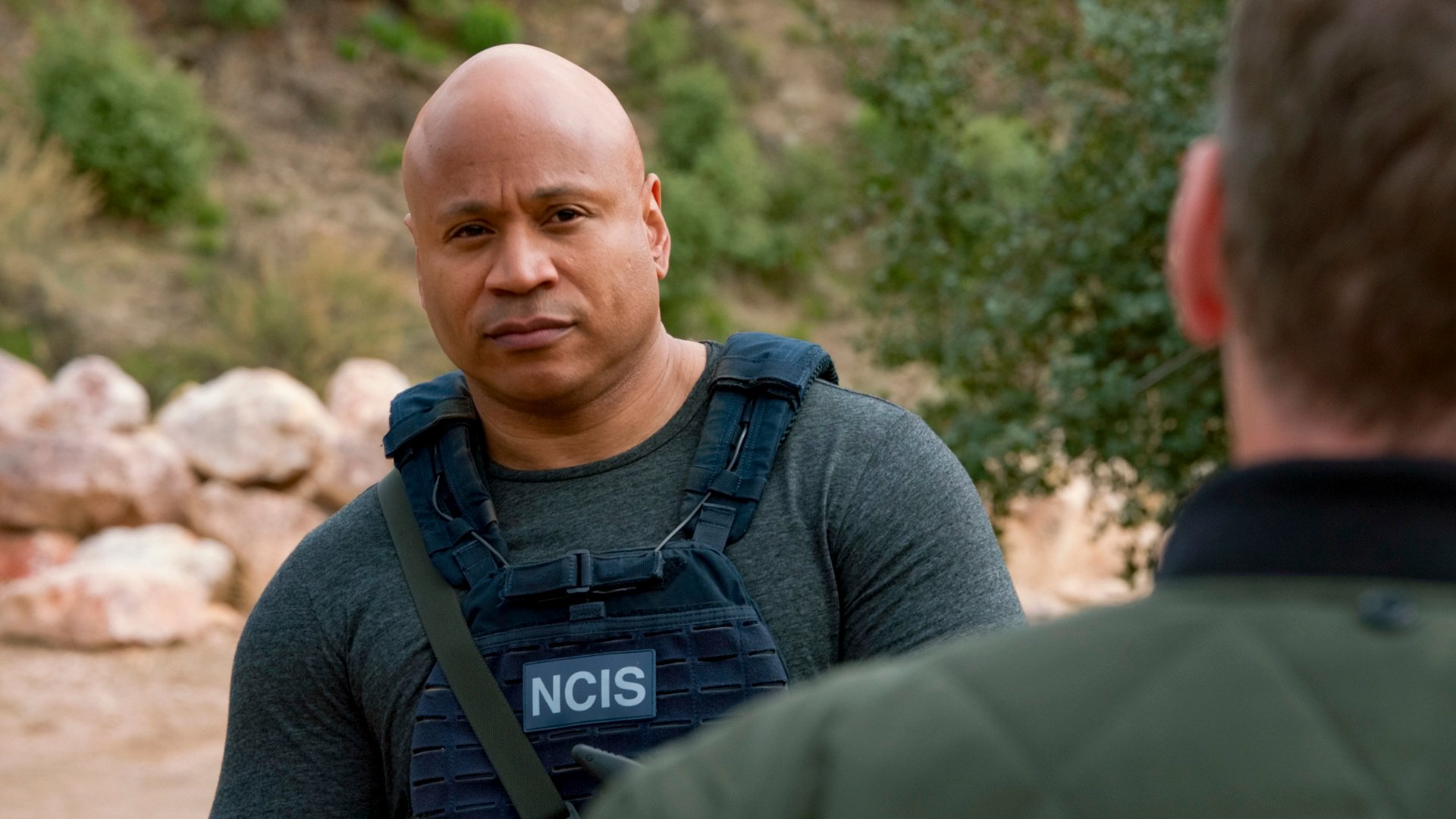 LL Cool J wears the NCIS uniform while talking to someone in the desert.
