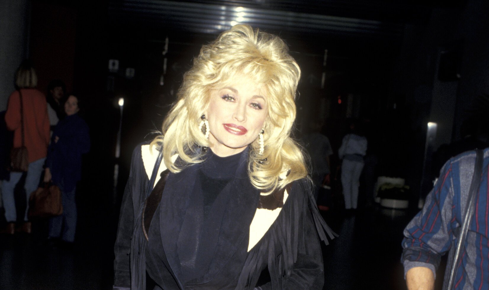 Dolly Parton at Los Angeles International Airport in 1993. She's in a black jacket and black top.