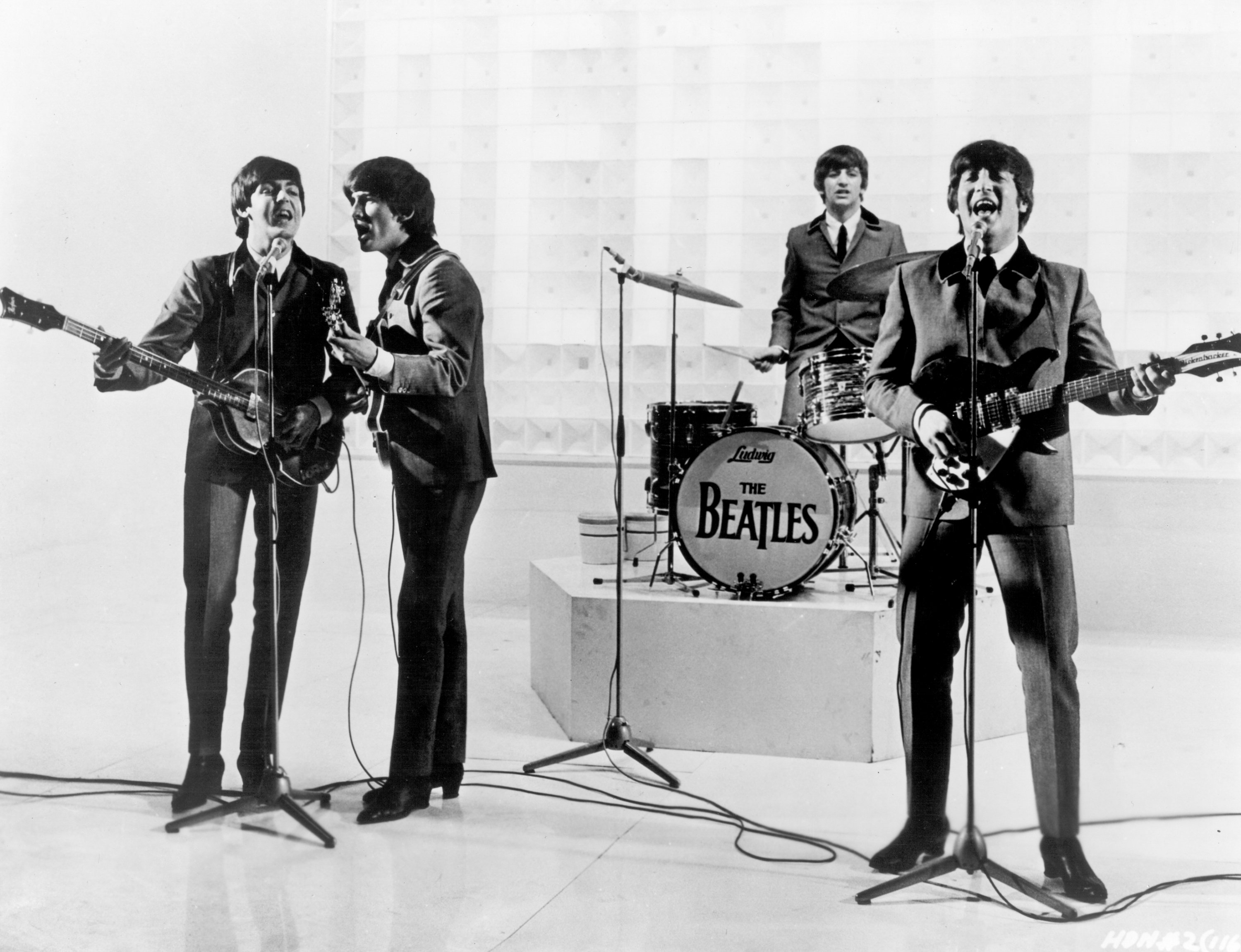 The Beatles' Paul McCartney, George Harrison, Ringo Starr, and John Lennon with a drum