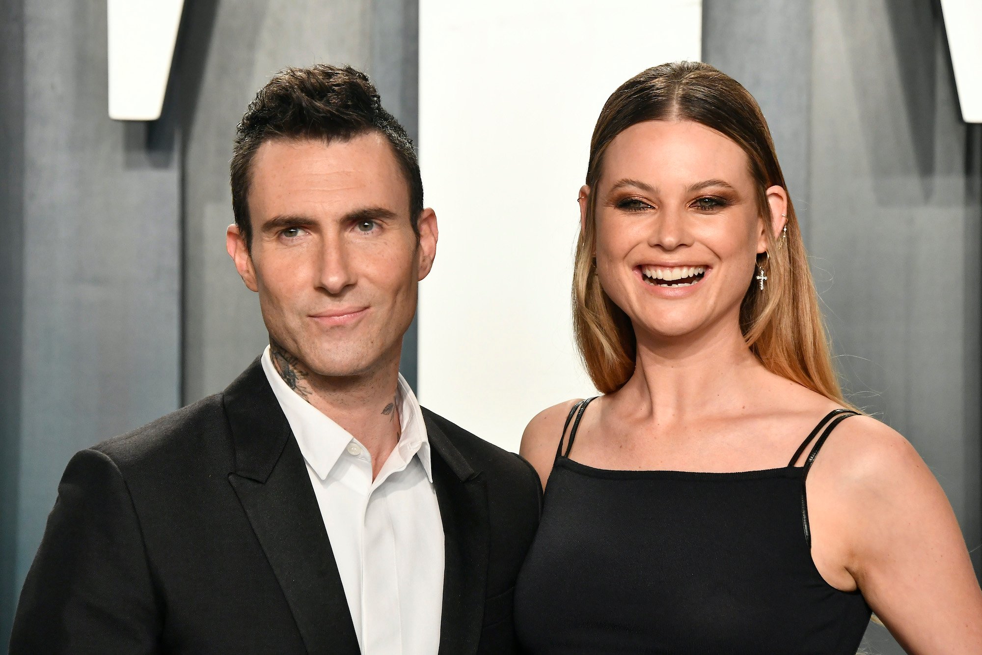 Adam Levine and Behati Prinsloo smiling in front of a blue background