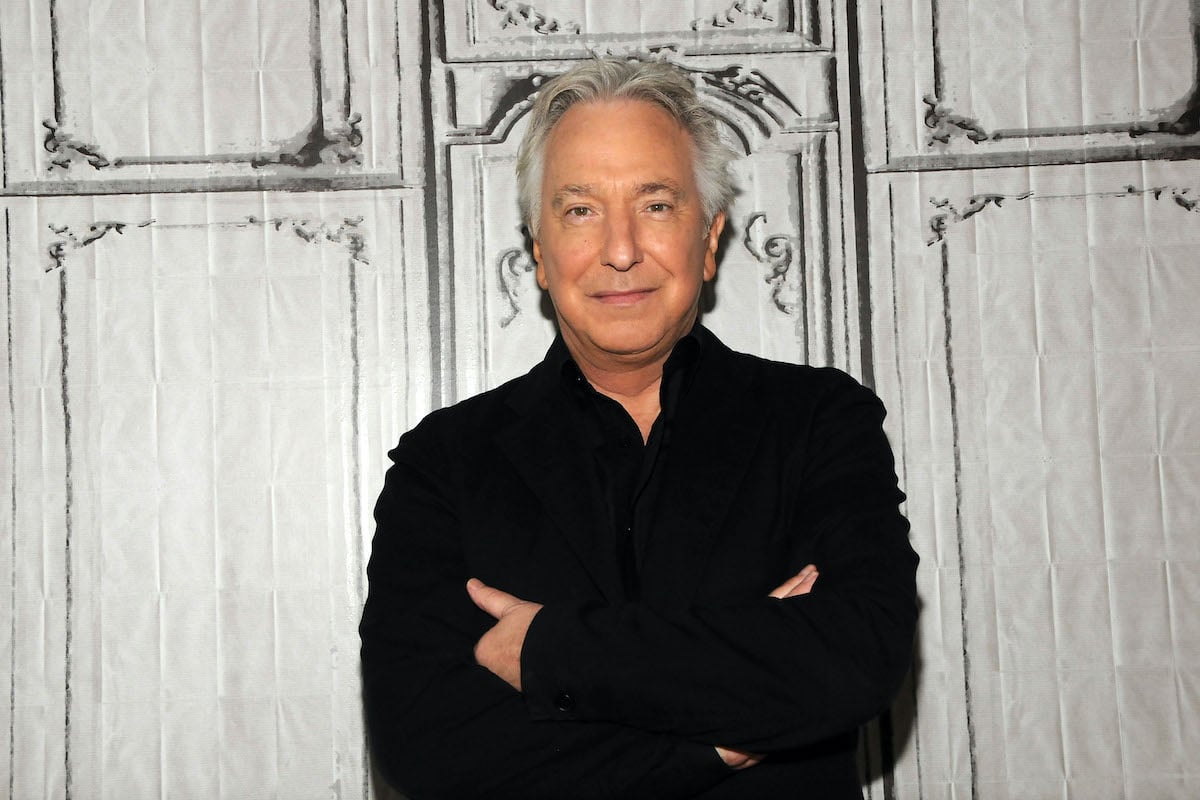 Alan Rickman wears black while he smiles and poses