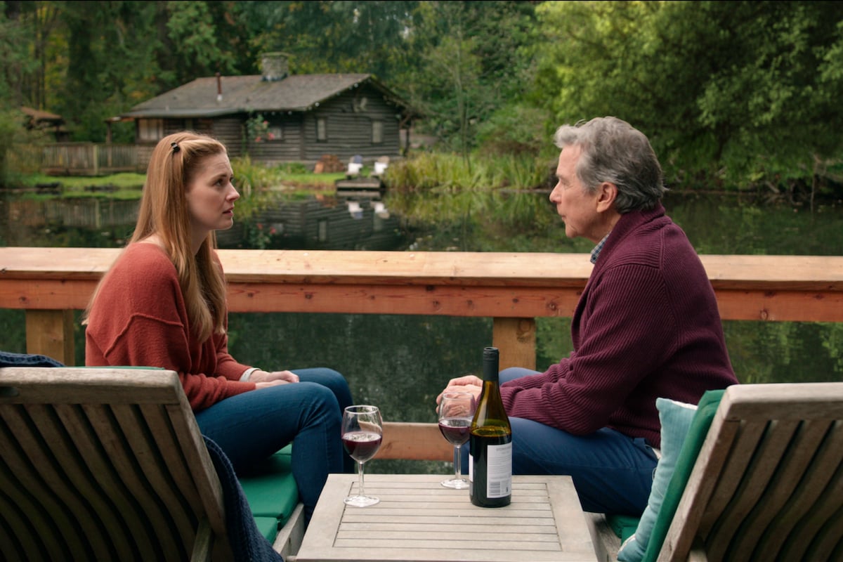 Alexandra Breckenridge as Mel Monroe and Tim Matheson as Doc Mullins sitting on a doc chatting in 'Virgin River'