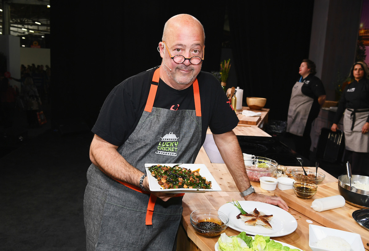 Andrew Zimmern holding a plate of food