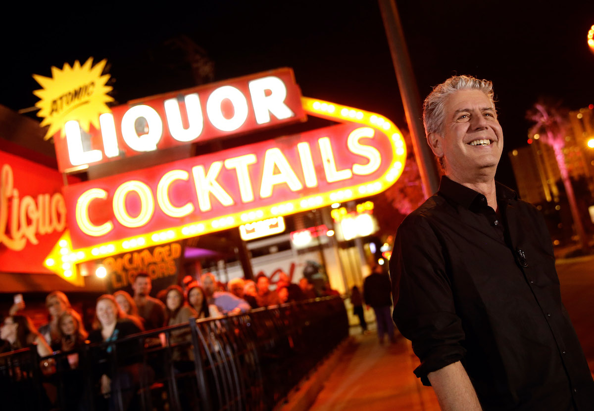 Anthony Bourdain standing in front of sign
