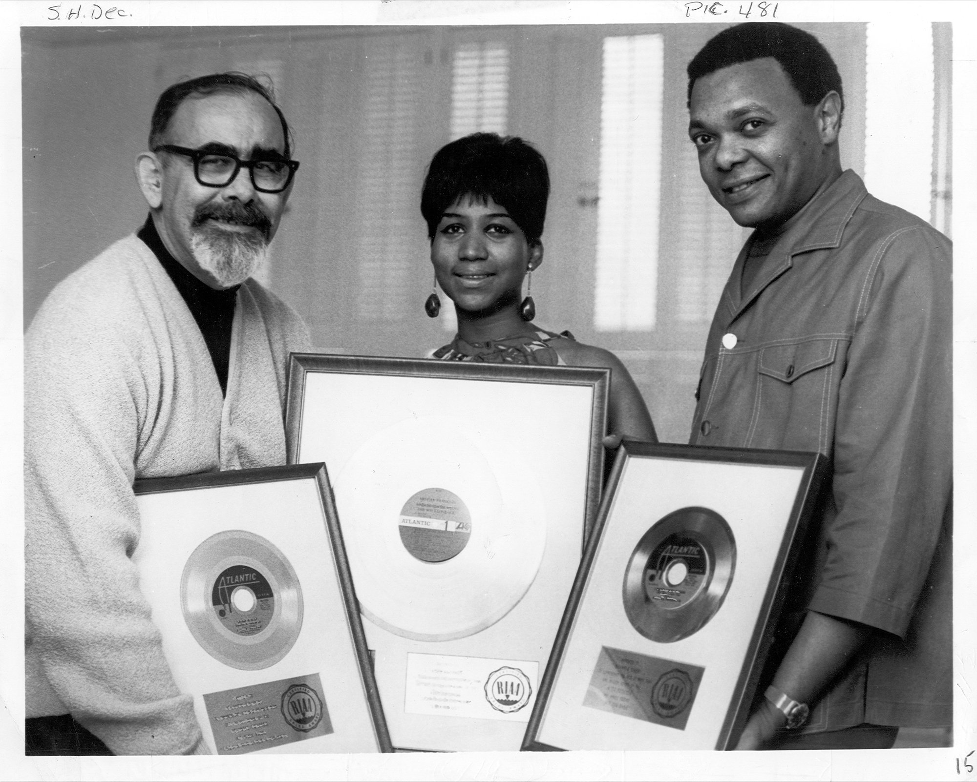 Aretha Franklin and Ted White holding framed records with producer Jerry Wexler in 1968