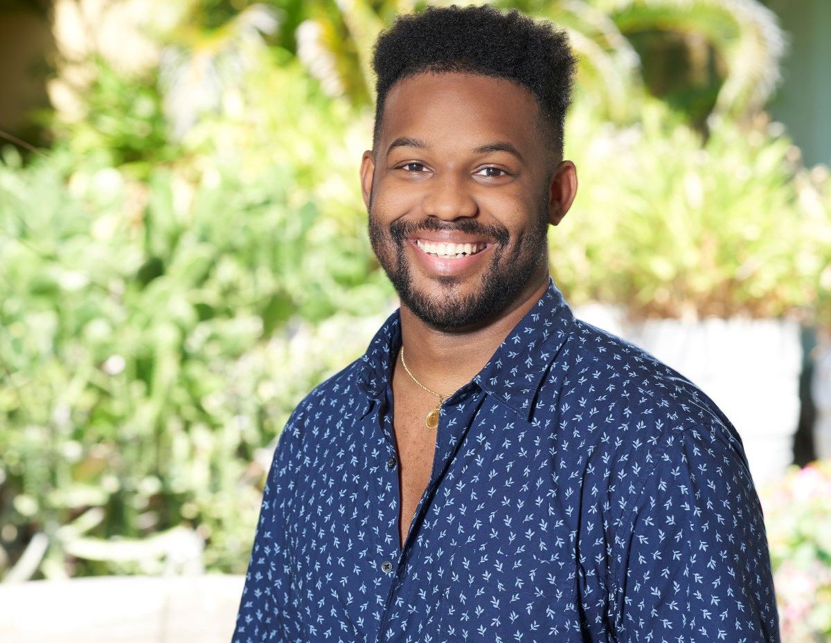 Tre Cooper of 'Bachelor in Paradise' smiles in a blue shirt in front of trees.
