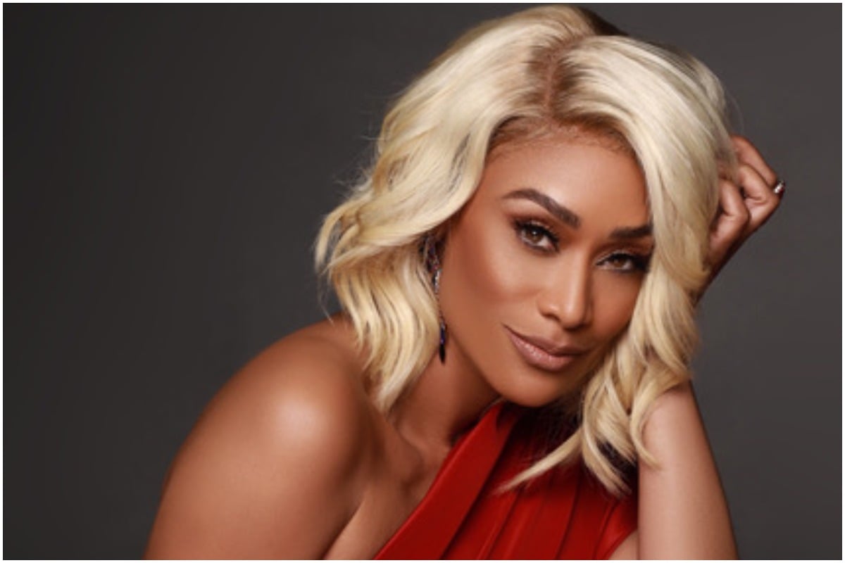 'Basketball Wives' alum Tami Roman wearing a red dress and smirking at the camera.