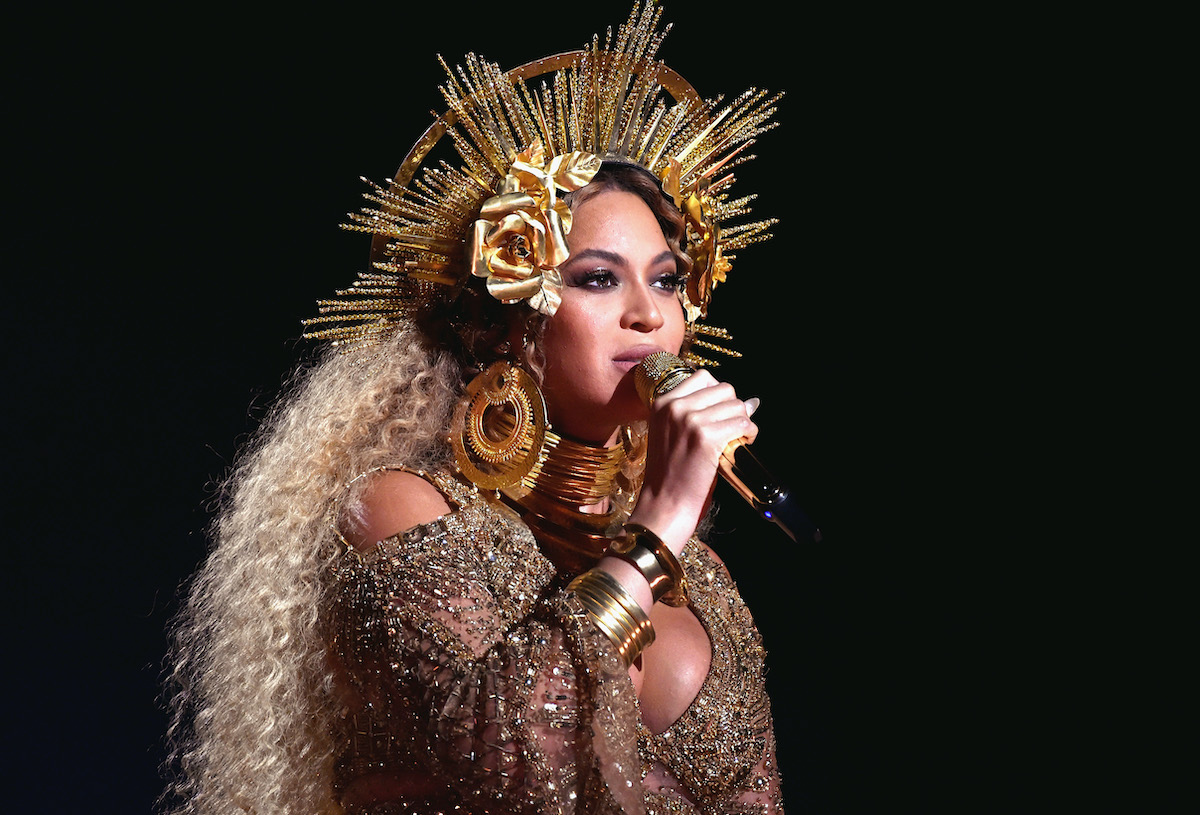 Beyoncé performing onstage in a gold dress and a matching headpiece