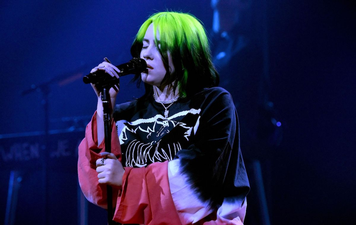 Billie EIlish performing onstage with green hair.