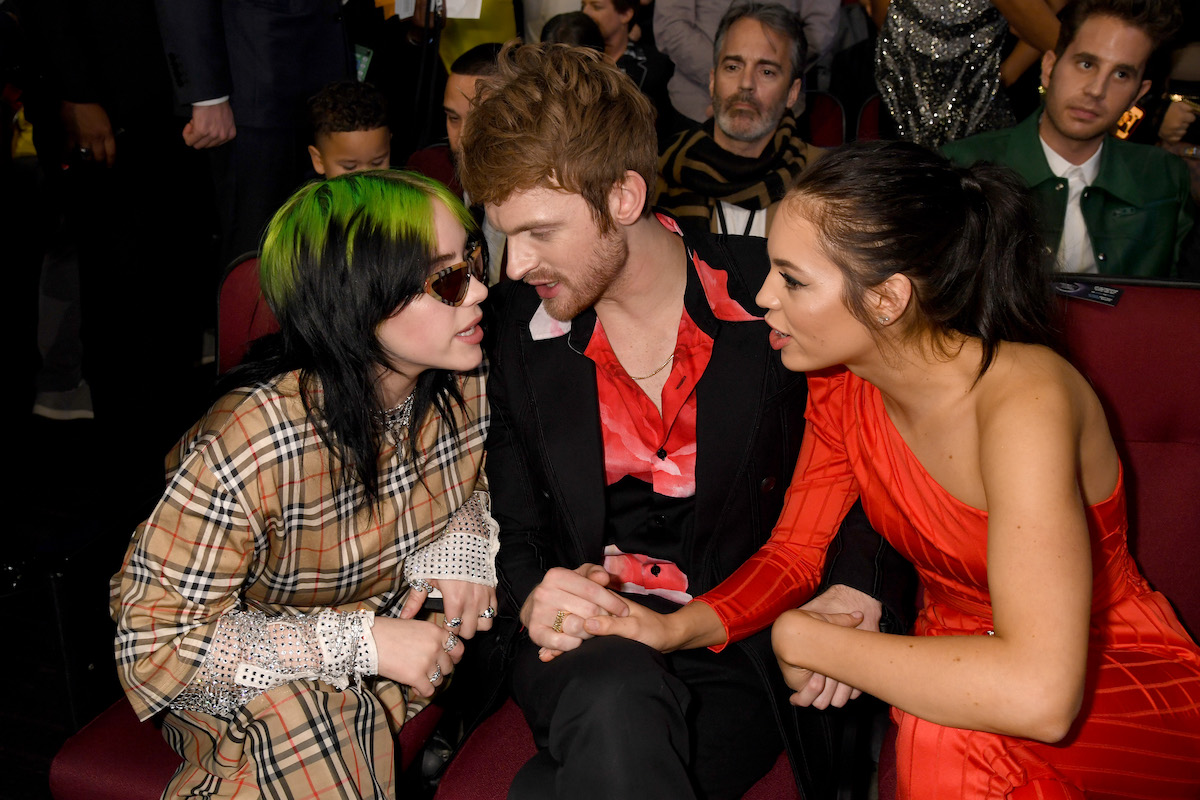 Billie Eilish, her brother Finneas, and his girlfriend Claudia Sulewski smile and laugh at an awards show.