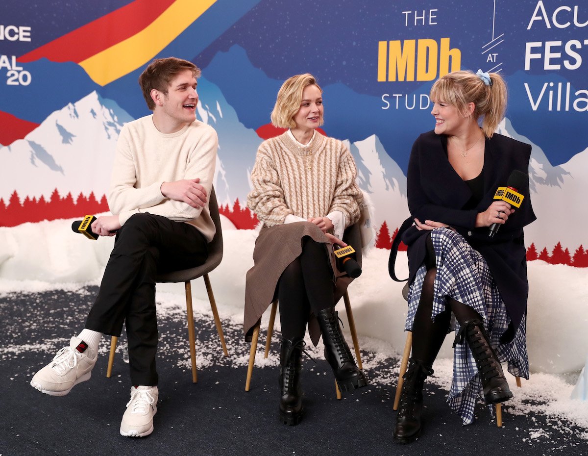 Bo Burnham, Carey Mulligan, and Emerald Fennell are seated side by side, holding microphones to answer questions at an event.