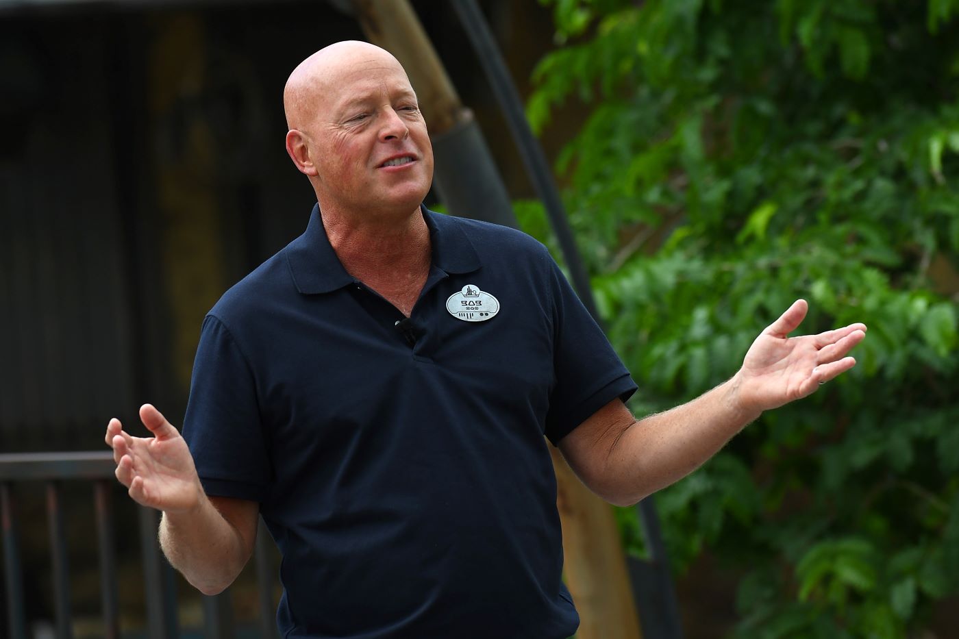 Bob Chapek, Disney's CEO, standing in a dark blue polo in front of a wooded area at a park in Disney, which is the creator of 'Shang-Chi'
