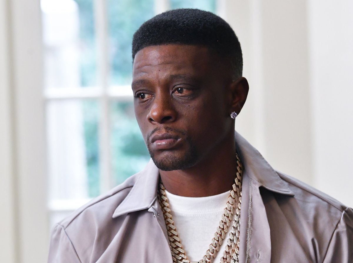 Boosie dressed in a light-colored shirt and gold chains on the set of a music video