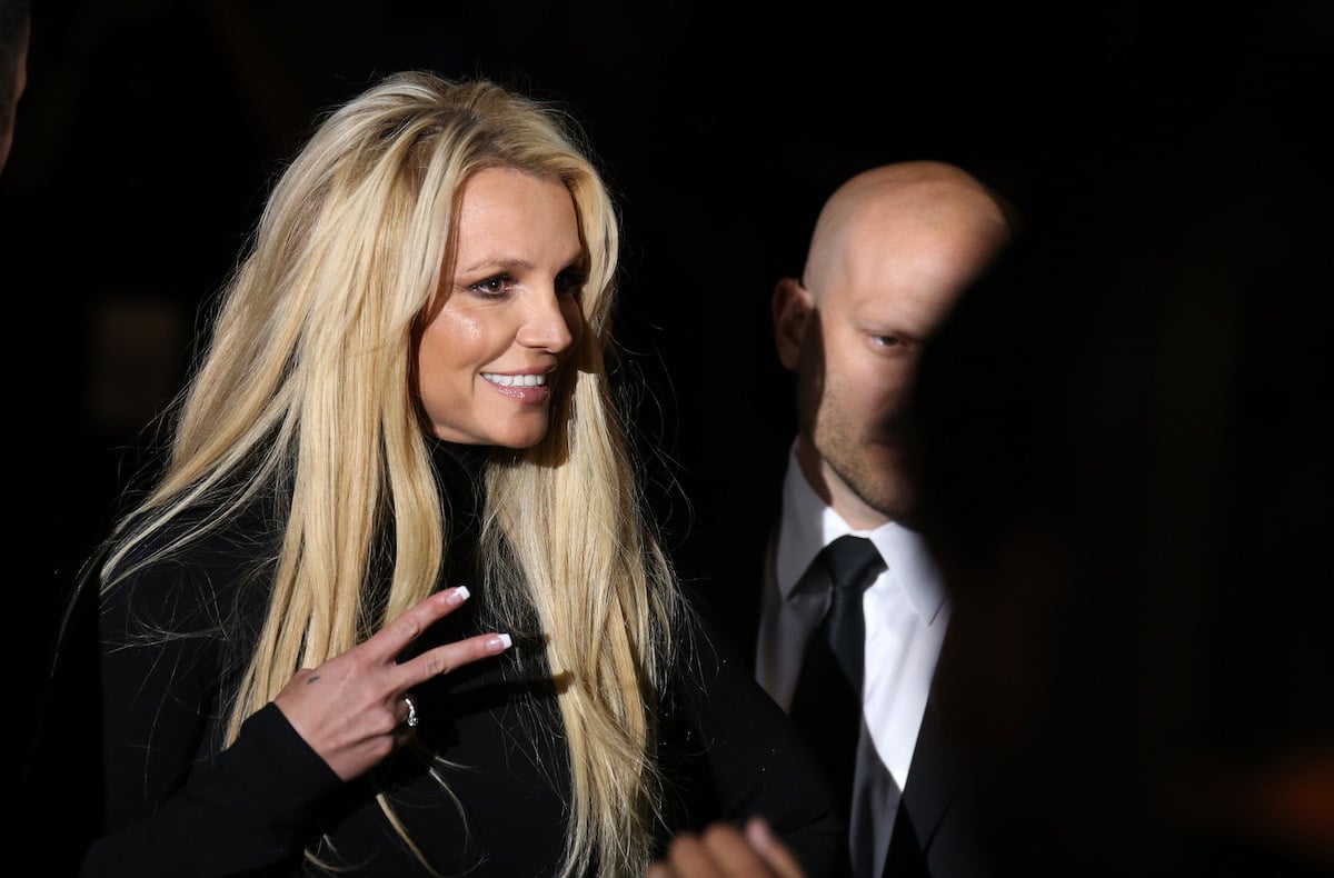 Britney Spears in black dress flashing peace sign