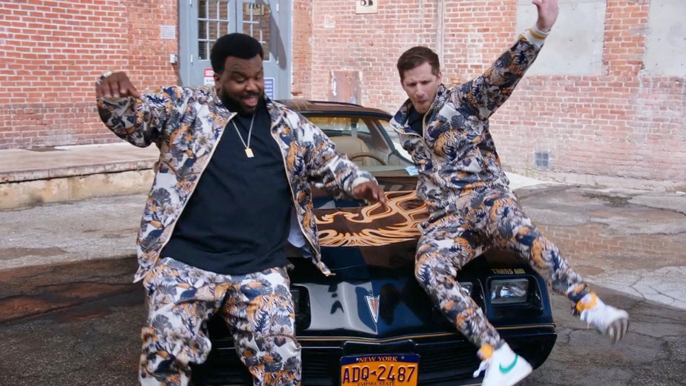 Doug Judy and Jake Peralta slide down the hood of a car in 'Brooklyn Nine-Nine'