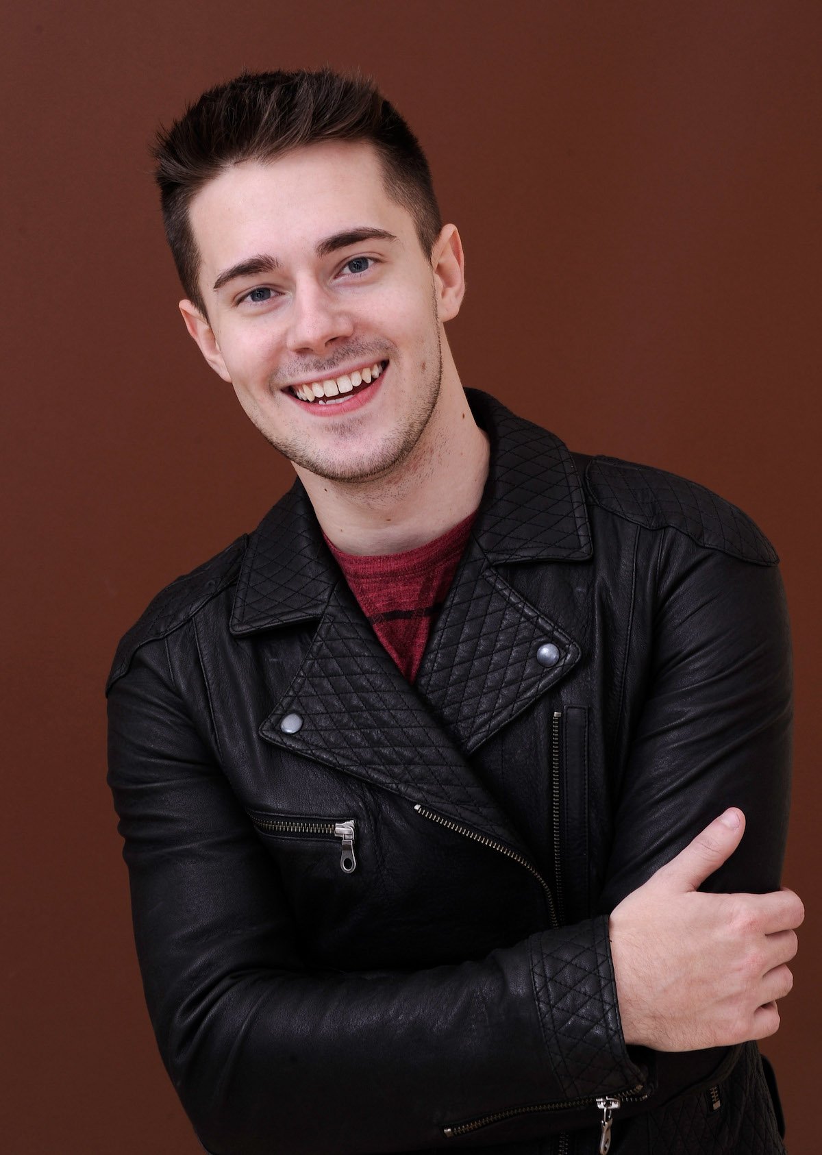 Chris Crocker in a black leather jacket, smiling and posing for the camera.