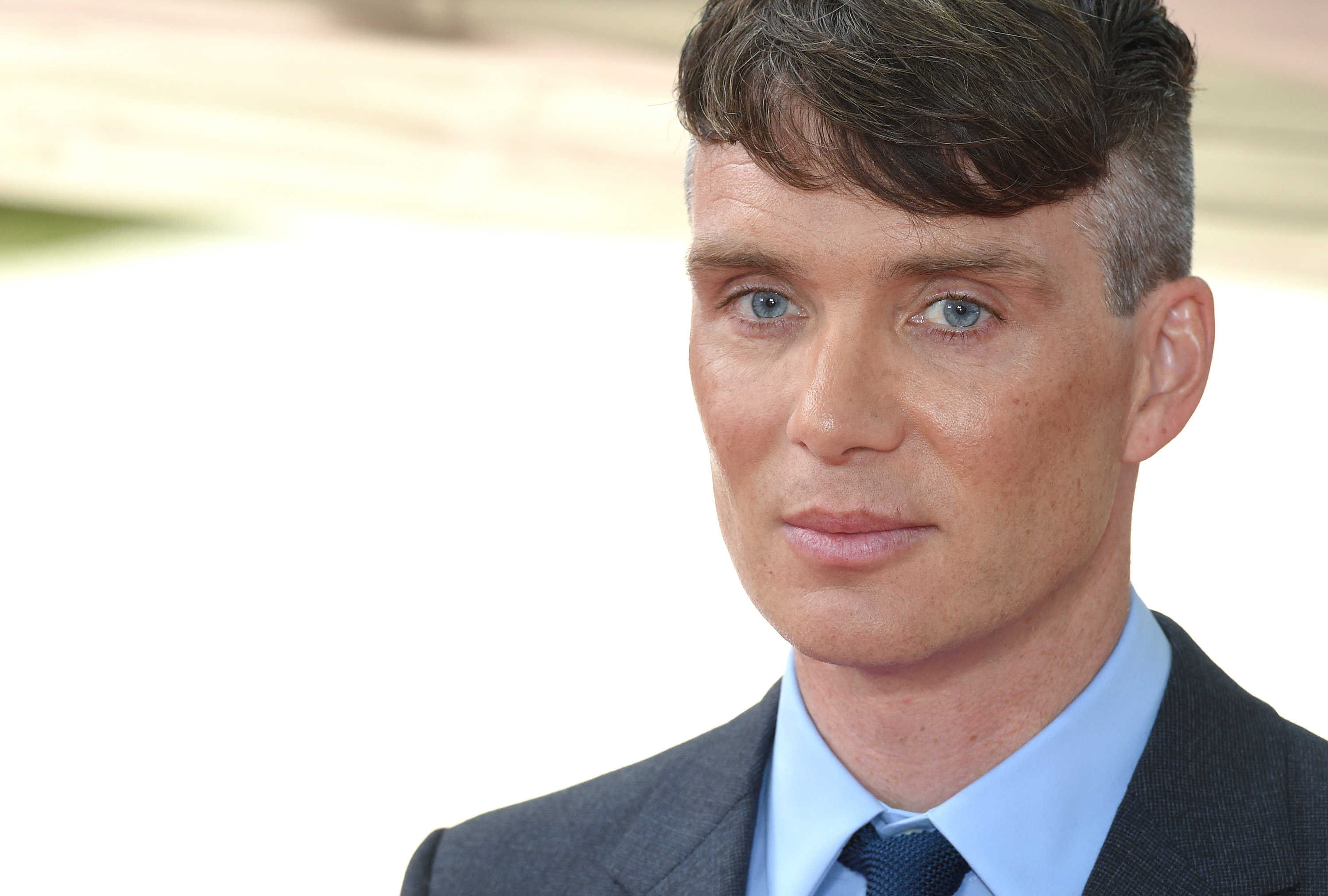A close-up photo of Cillian Murphy with very blue eyes in a suit.