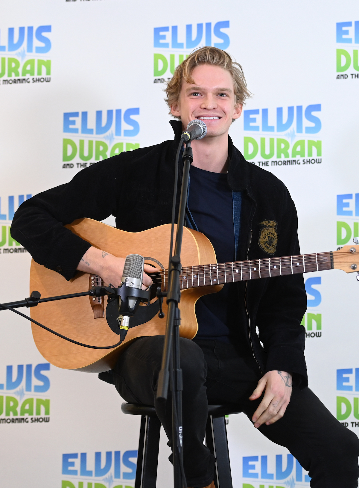 Cody Simpson playing a guitar and singing in front of a microphone.