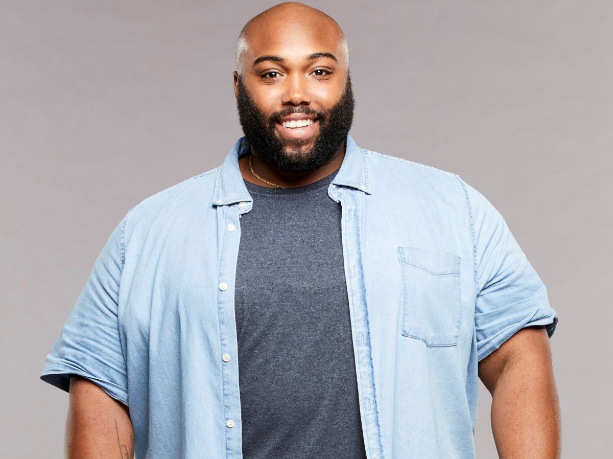 Derek Frazier of 'Big Brother' stands smiling in a blue under shirt and blue button up.