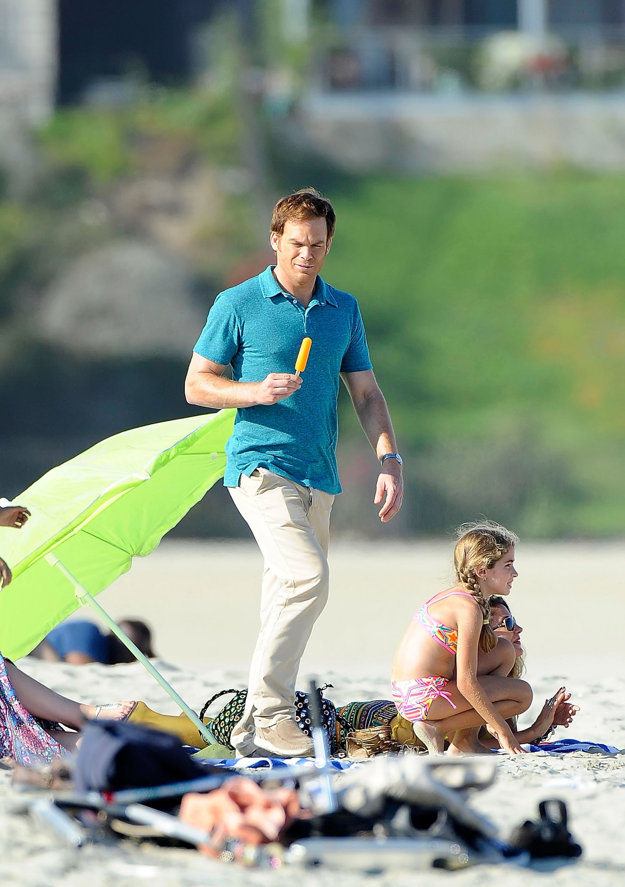 Michael C. Hall as Dexter Morgan is seen walking on the beach, holding an ice pop while filming a scene for 'Dexter'