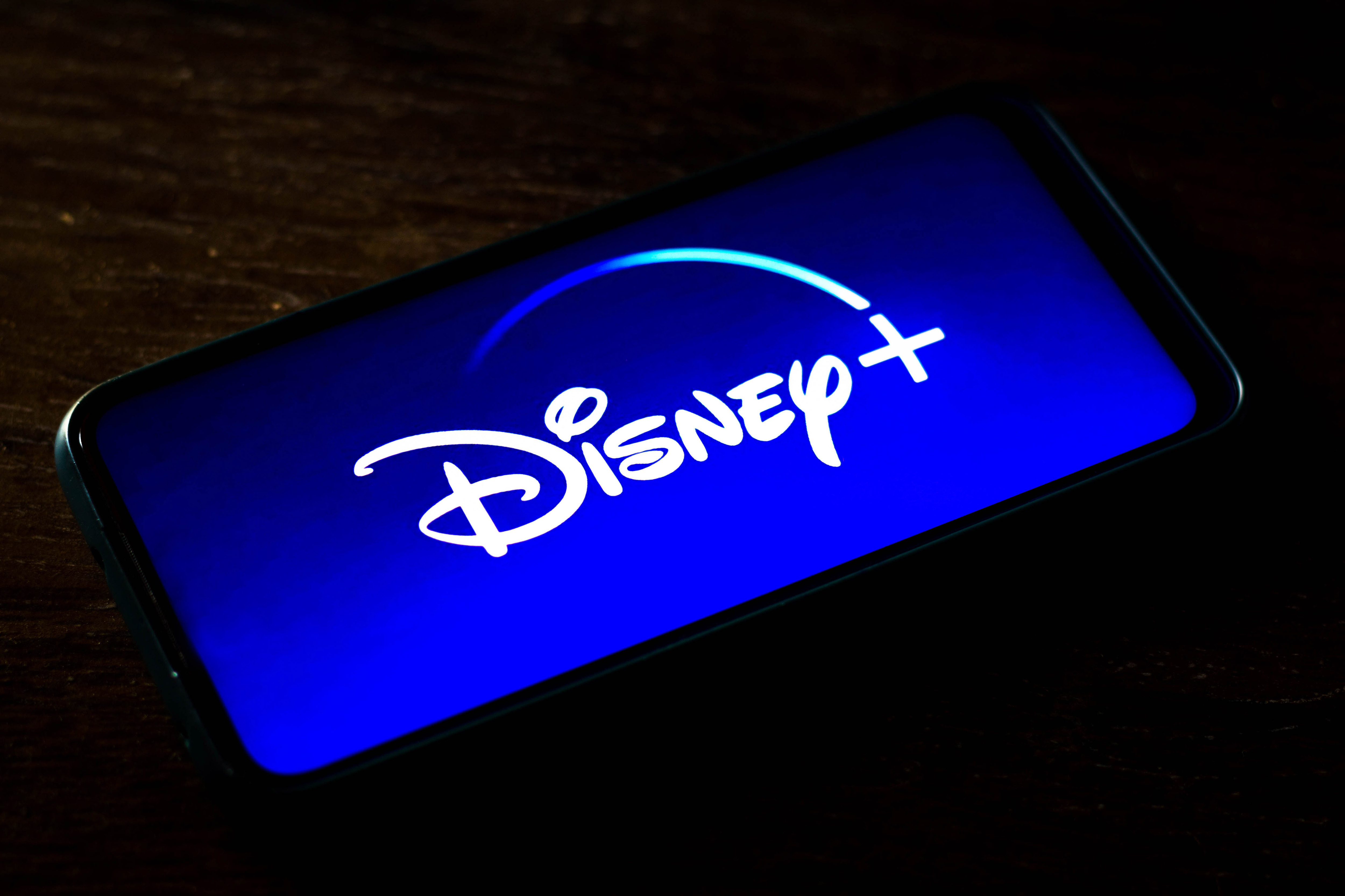 Photo illustration the Disney+ logo seen displayed on a smartphone screen