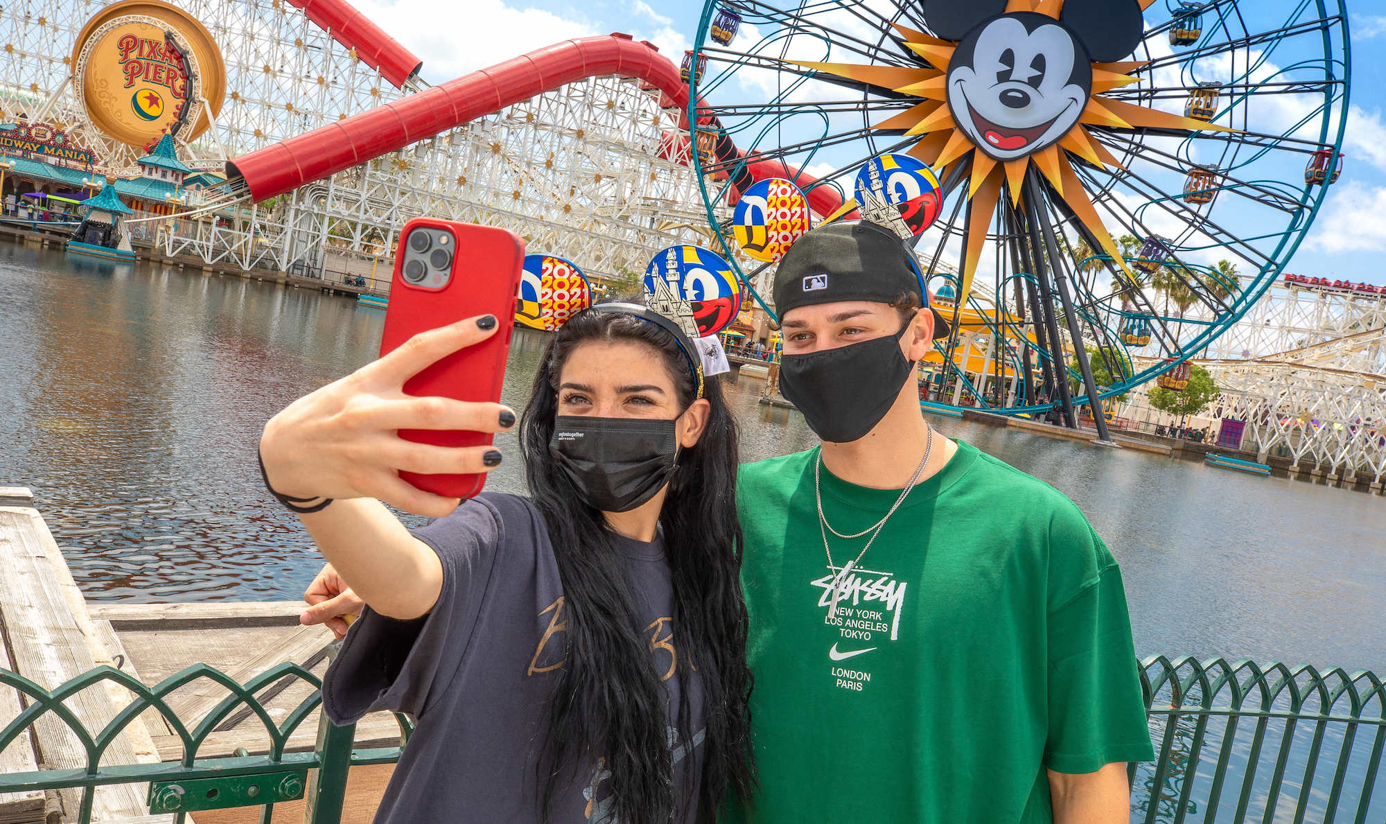 Dixie D'Amelio and Noah Beck taking a selfie in front of a ferris wheel at Disneyland