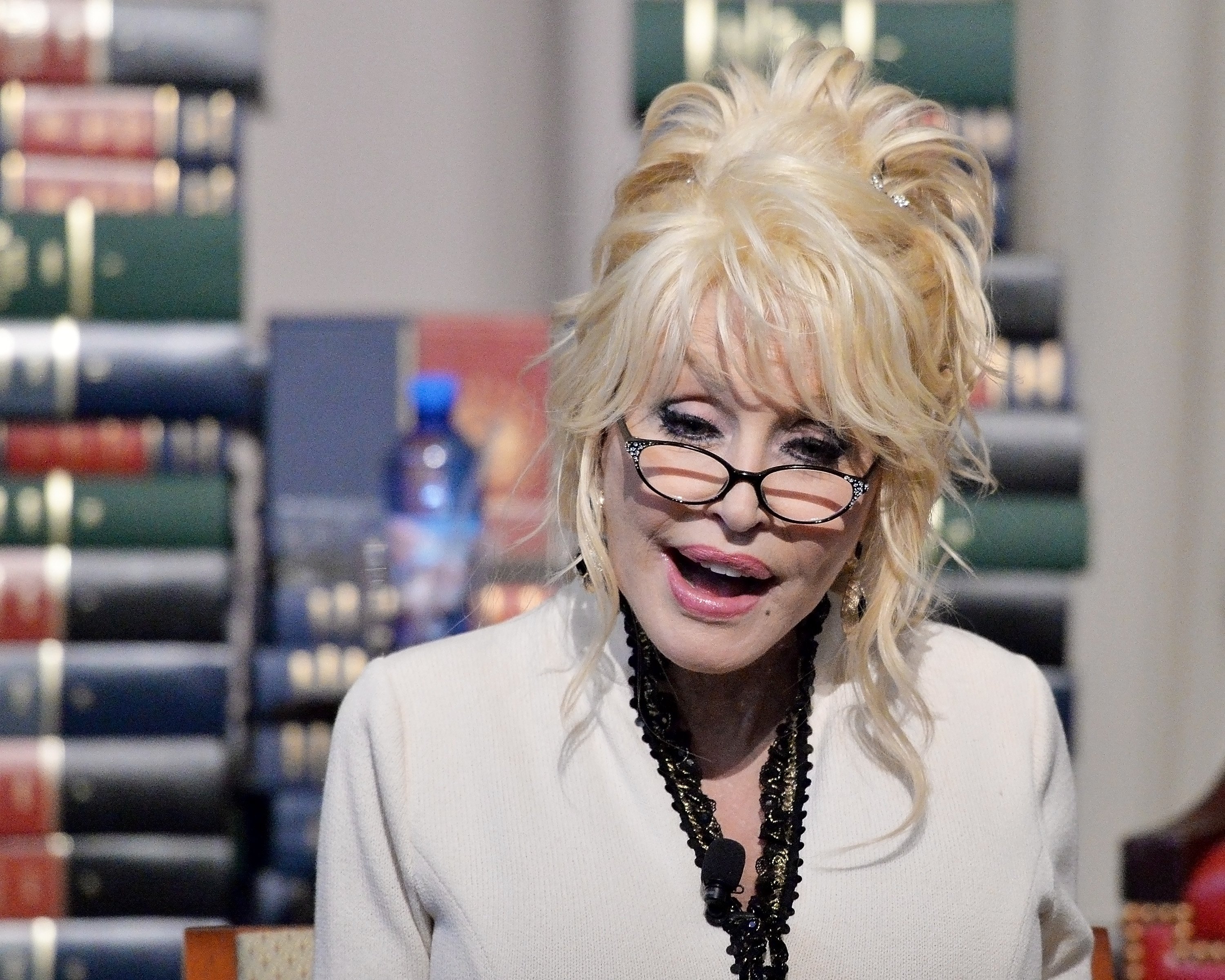 Dolly Parton in front of stacks of books for the Imagination Library.