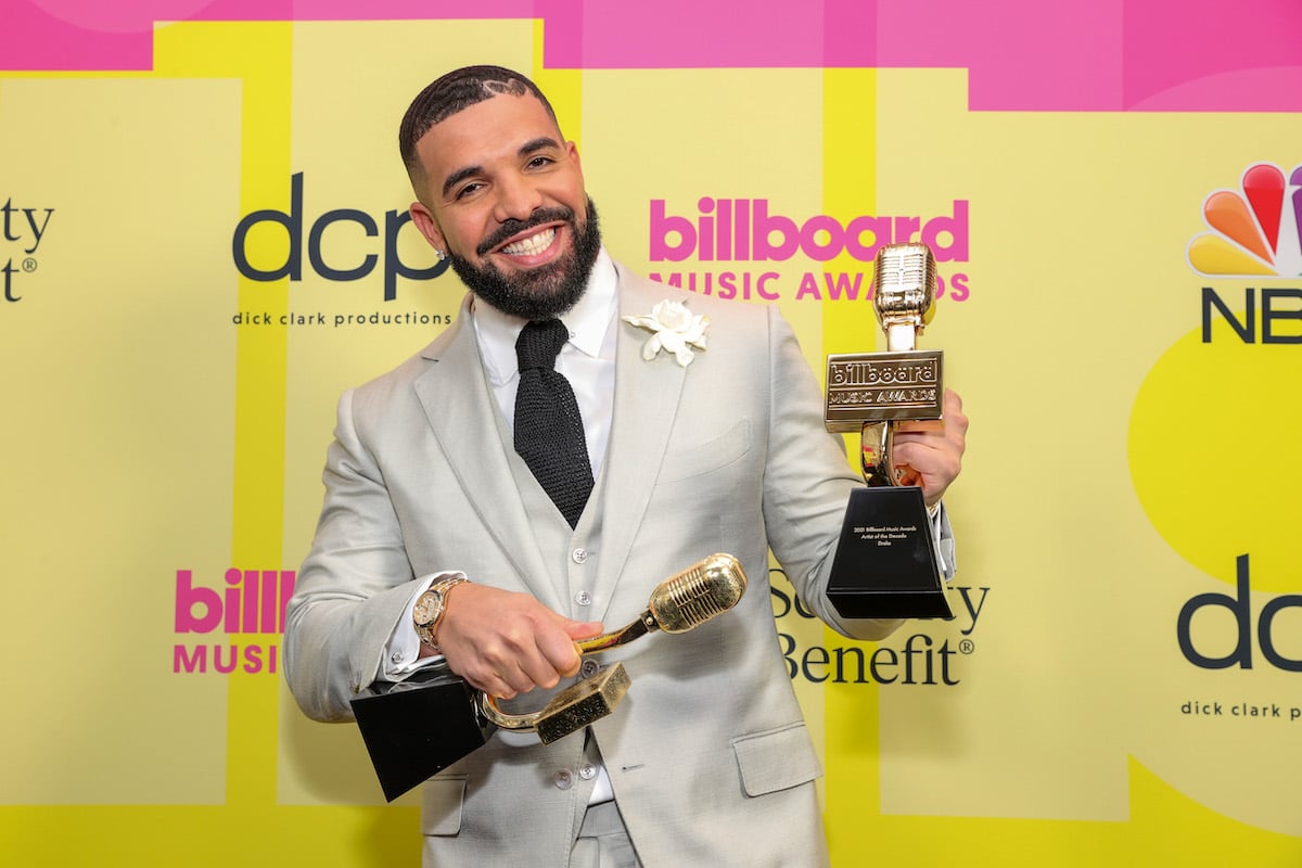Drake poses with awards in a cream suit while smiling as winner of the Artist of the Decade Award, poses backstage for the 2021 Billboard Music Awards, broadcast on May 23, 2021 at Microsoft Theater in Los Angeles, California.