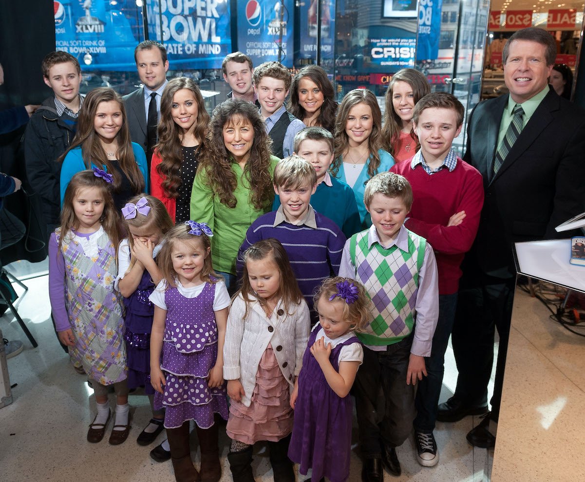 The Duggar family crowded together and smiling at the camera on the set of 'Extra' to discuss Duggar news