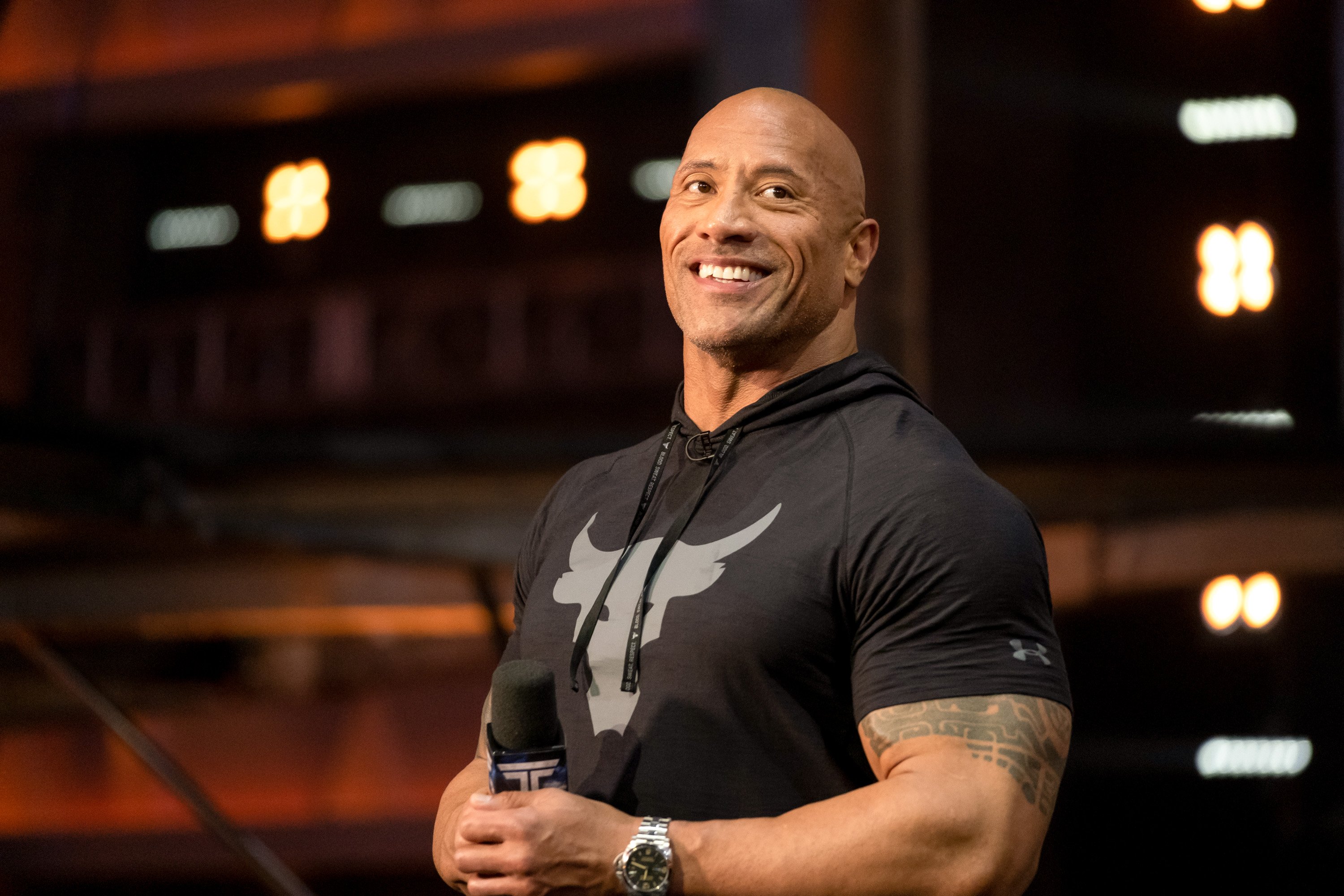 'Jungle Cruise' and 'Black Adam' star Dwayne the Rock Johnson. He's standing in a black t-shirt and smiling at the camera.