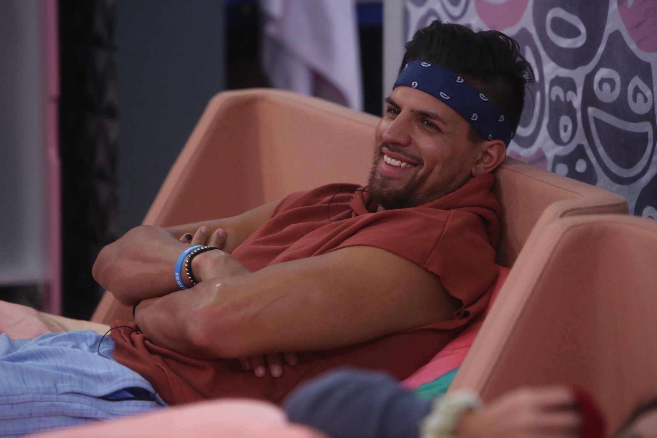 Fessy Shafaat, part of MTV's 'The Challenge' Season 37 cast, laughing while sitting on a couch in the 'Big Brother' house
