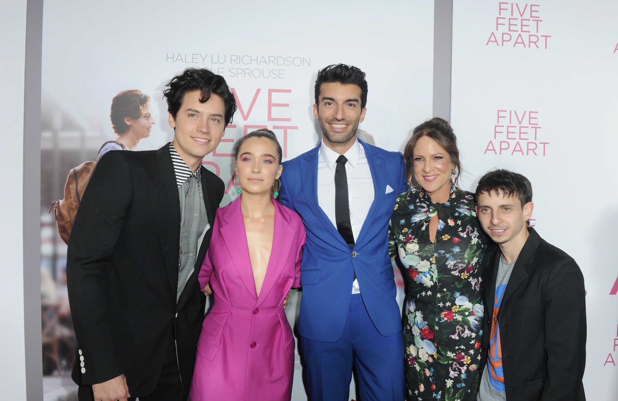 Cast members of 'Five Feet Apart' posing in front of a poster for the film