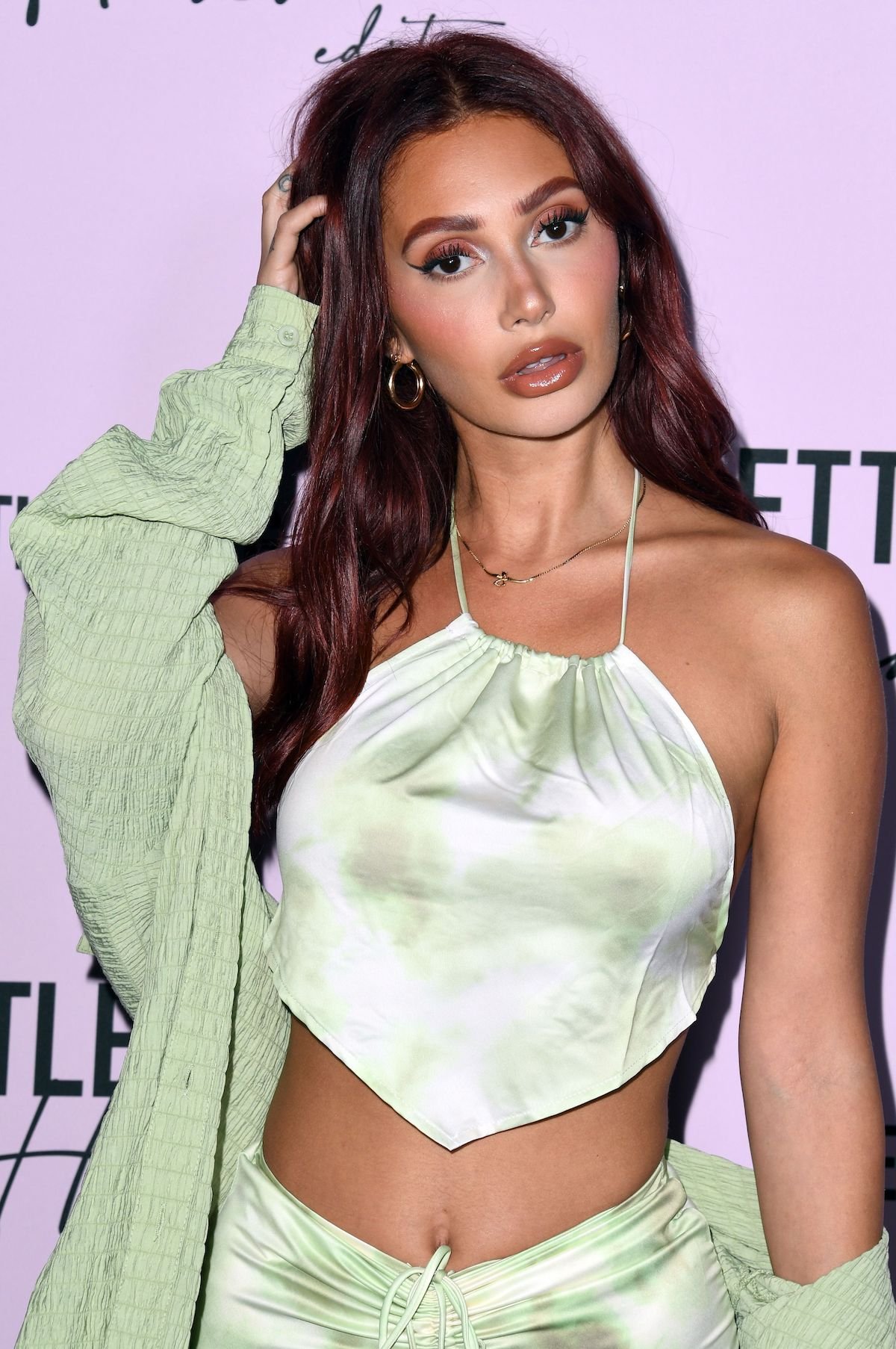 Francesca Farago, dressed casually, pushes her hair back and poses for the camera at an event.