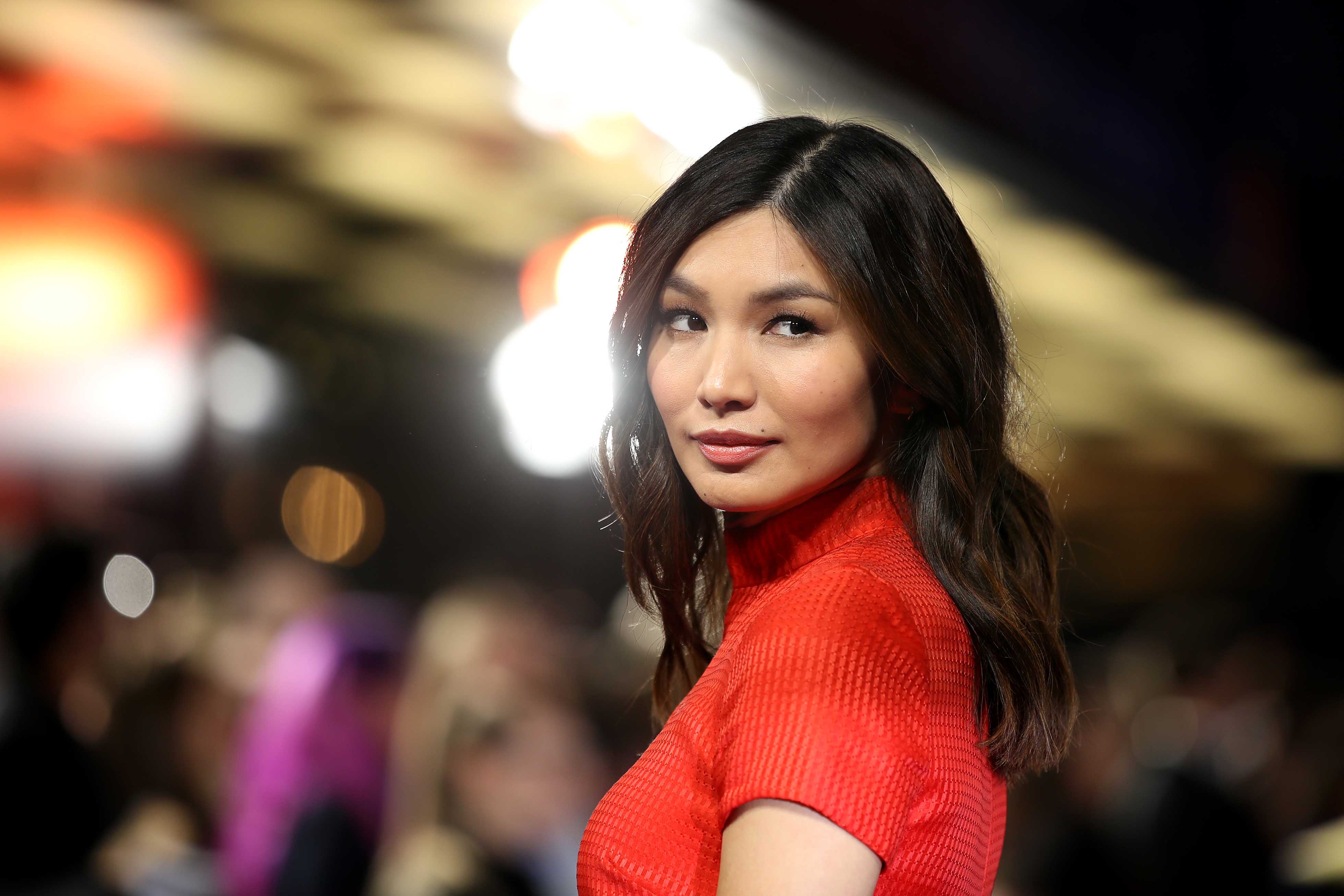 ‘Eternals’ star Gemma Chan from the chest up wearing a red top and looking over her left shoulder.
