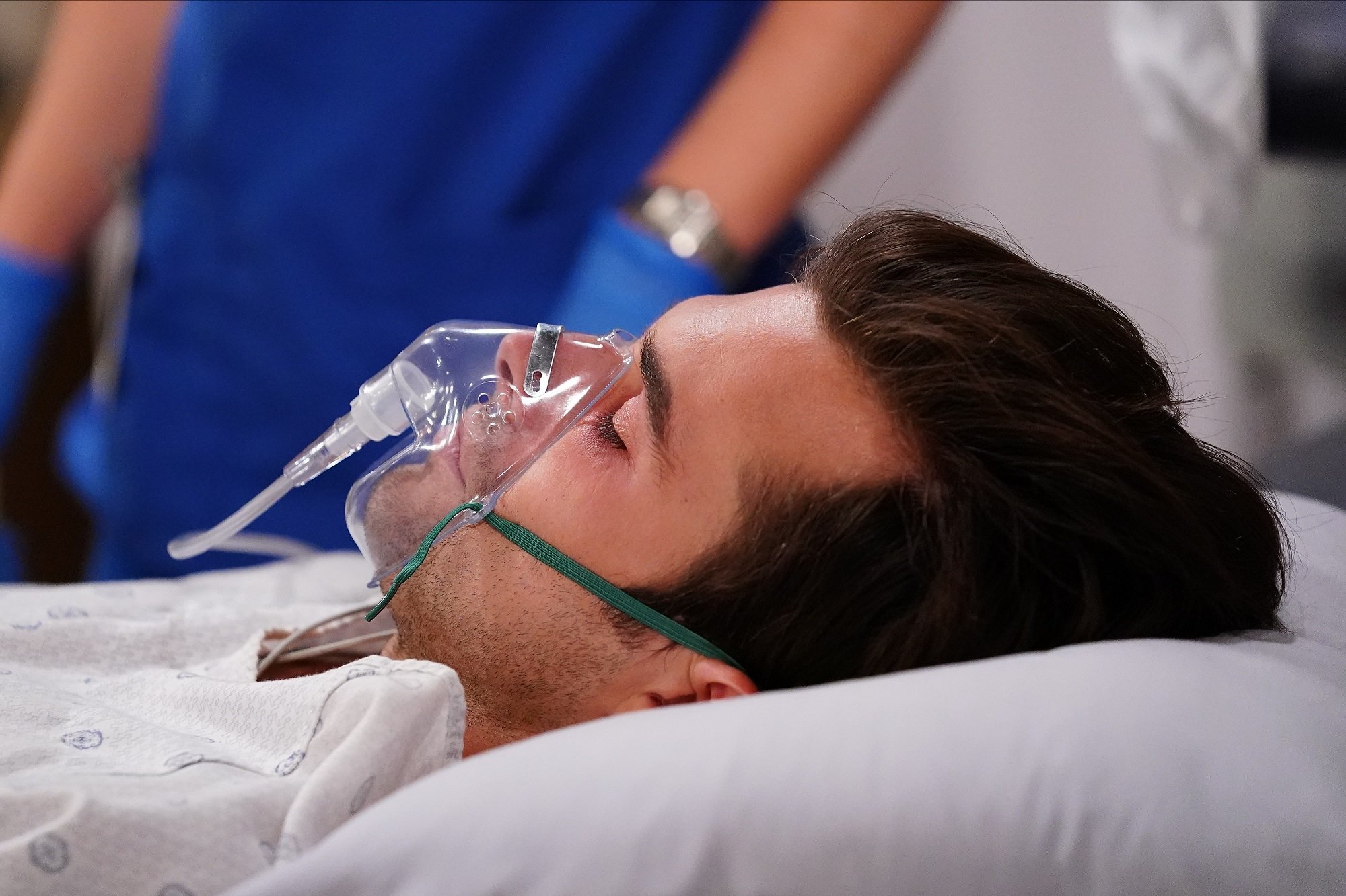 A scene from 'General Hospital' with a cast member lying in a hospital bed with an oxygen mask