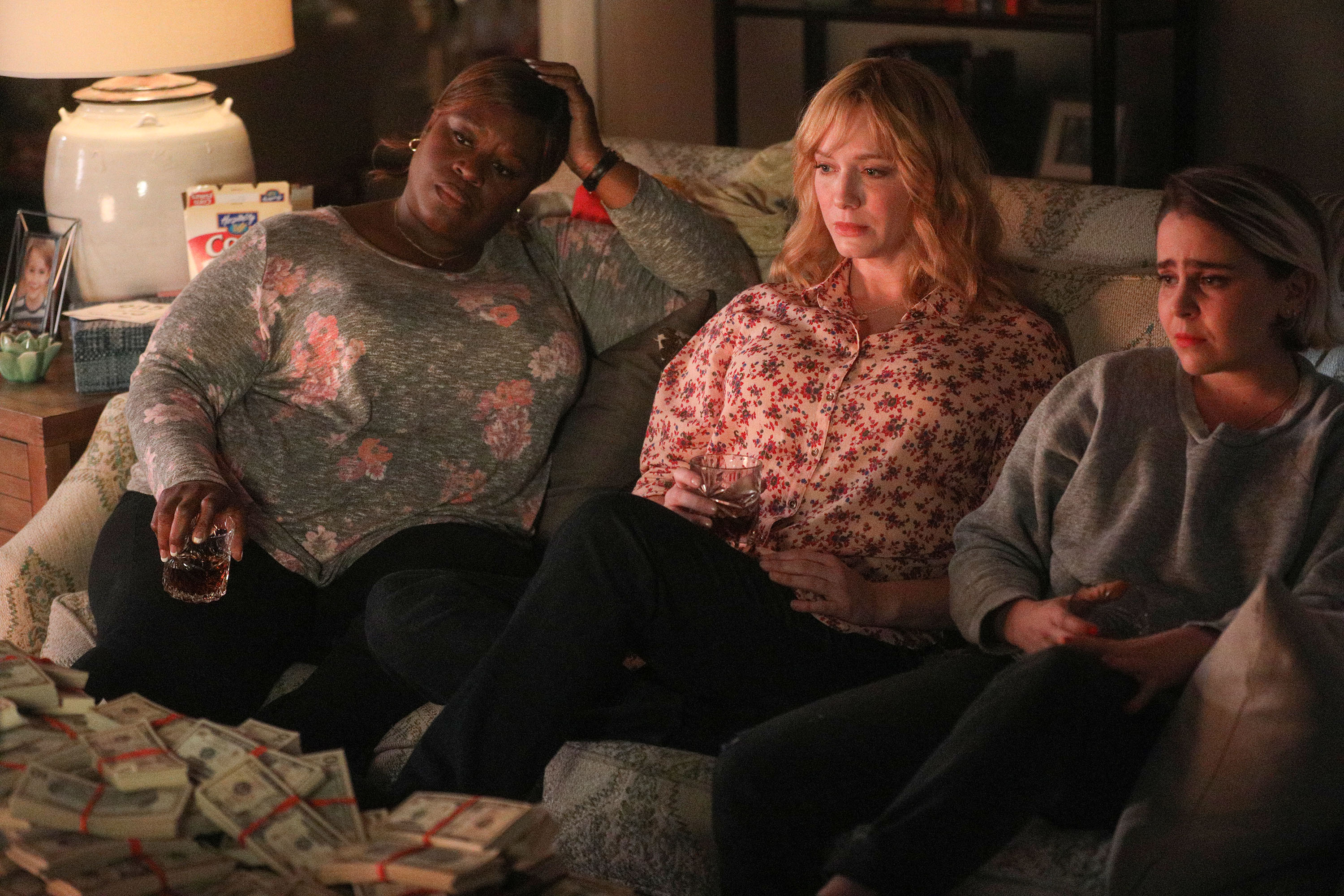 'Good Girls' stars Retta as Ruby Hill, Christina Hendricks as Beth Boland, and Mae Whitman as Annie Marks sitting on a couch frowning.
