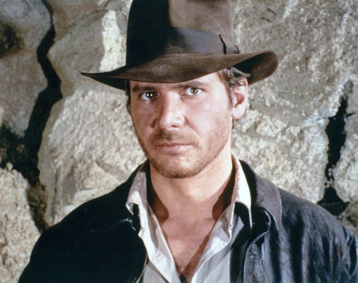 Harrison Ford wears a brown fedora and poses as Indiana Jones