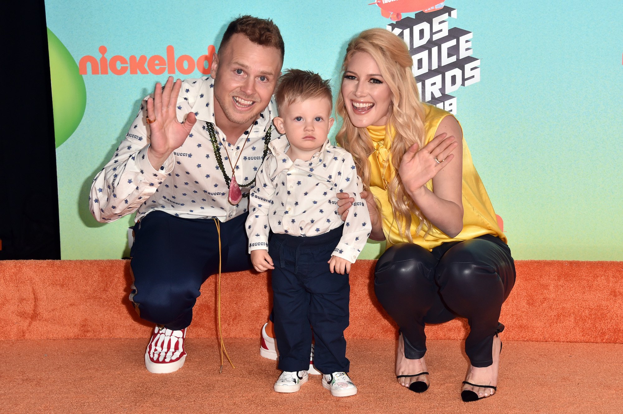 (L-R) Spencer Pratt, Gunner Stone, and Heidi Montag smiling in front of a blue background