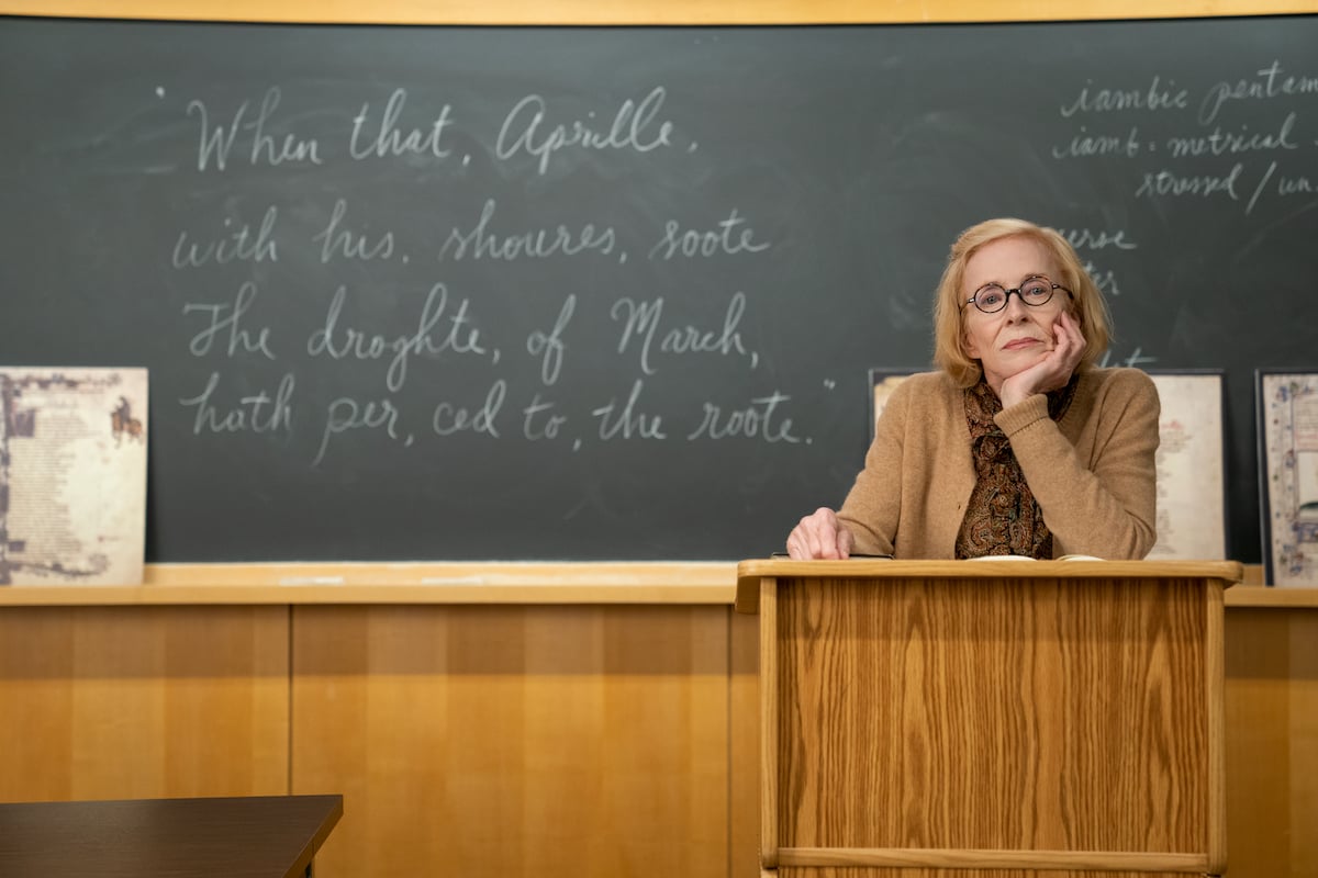 Holland Taylor stands behind a lectern with her chin resting in the palm of her hand as professor Joan Hambling in 'The Chair' Season 1