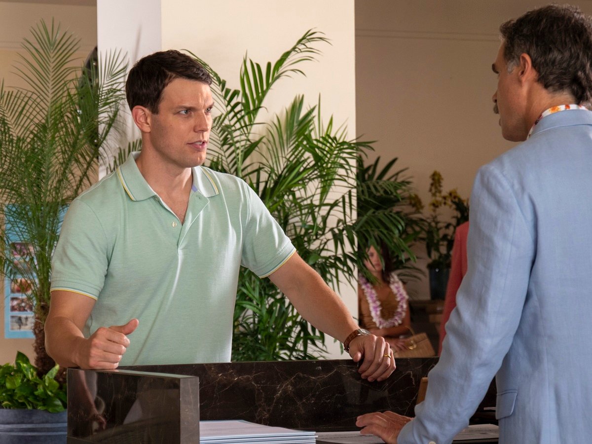 Jake Lacy in a teal shirt speaks to Murray Bartlett in a blue suit in 'The White Lotus.'