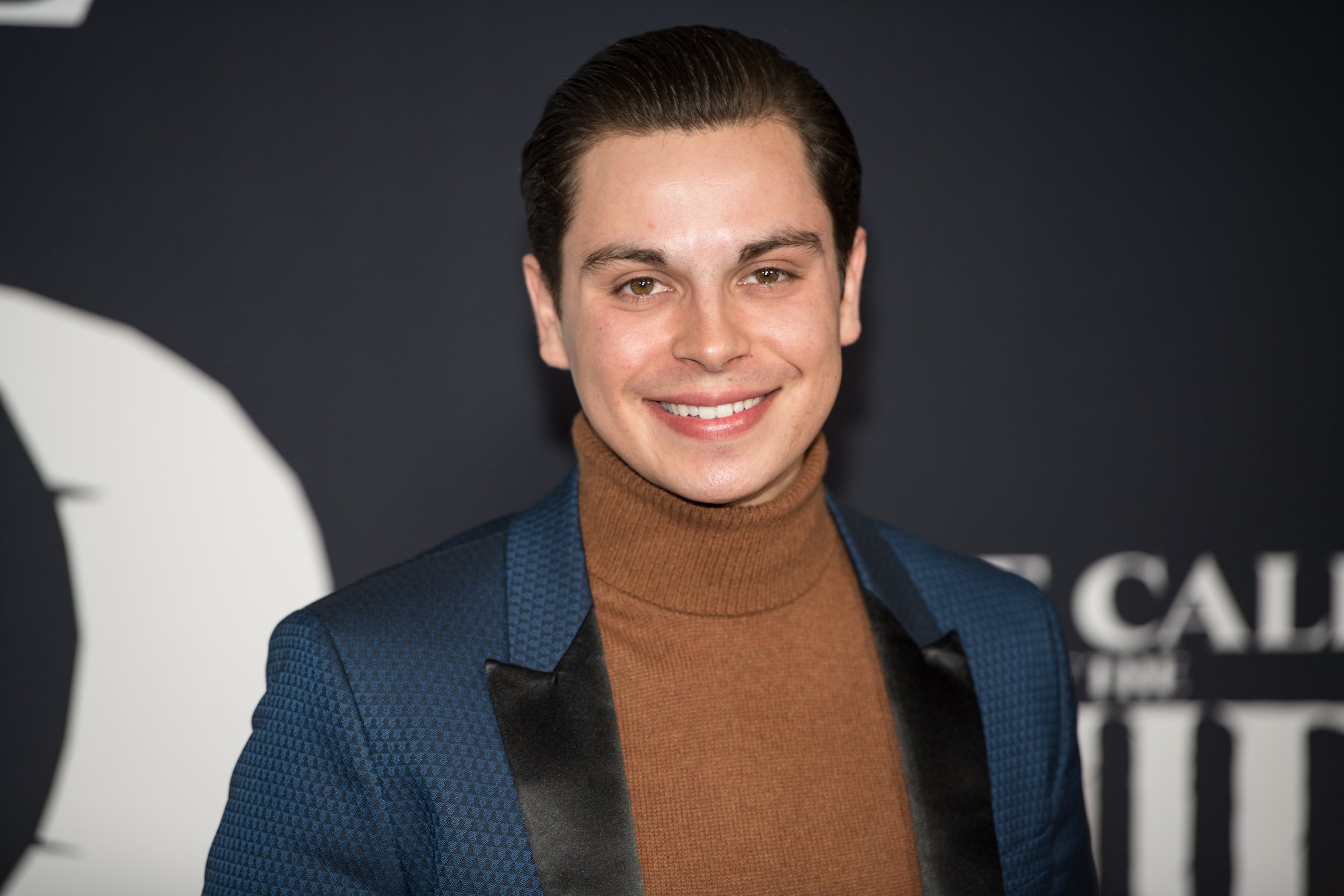 Jake T. Austin smiling in front of a black background