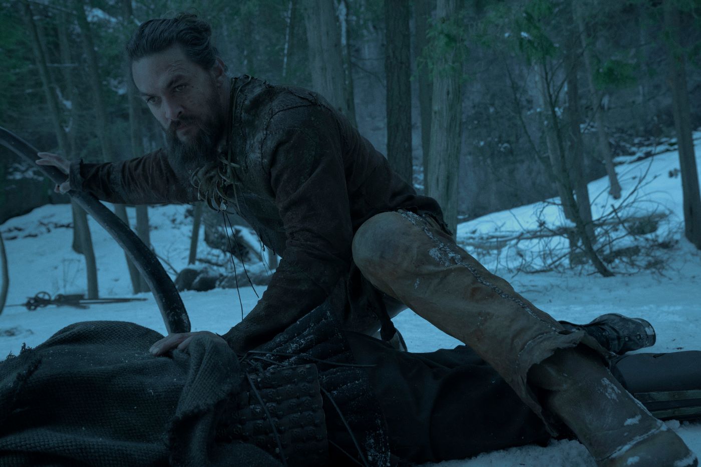 Jason Momoa crouches in the snow during a scene in the show 'See.'