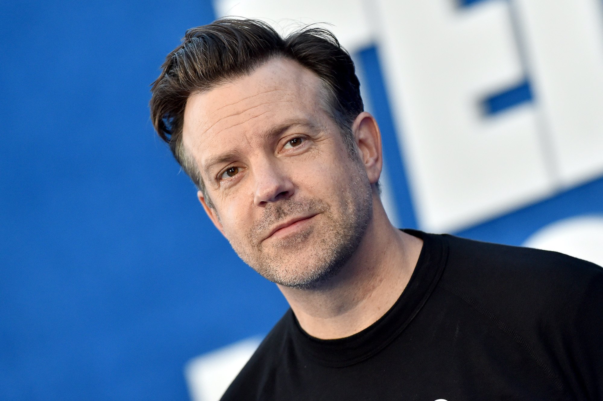 Jason Sudeikis poses for cameras in a black shirt at the season 2 premiere of 'Ted Lasso'