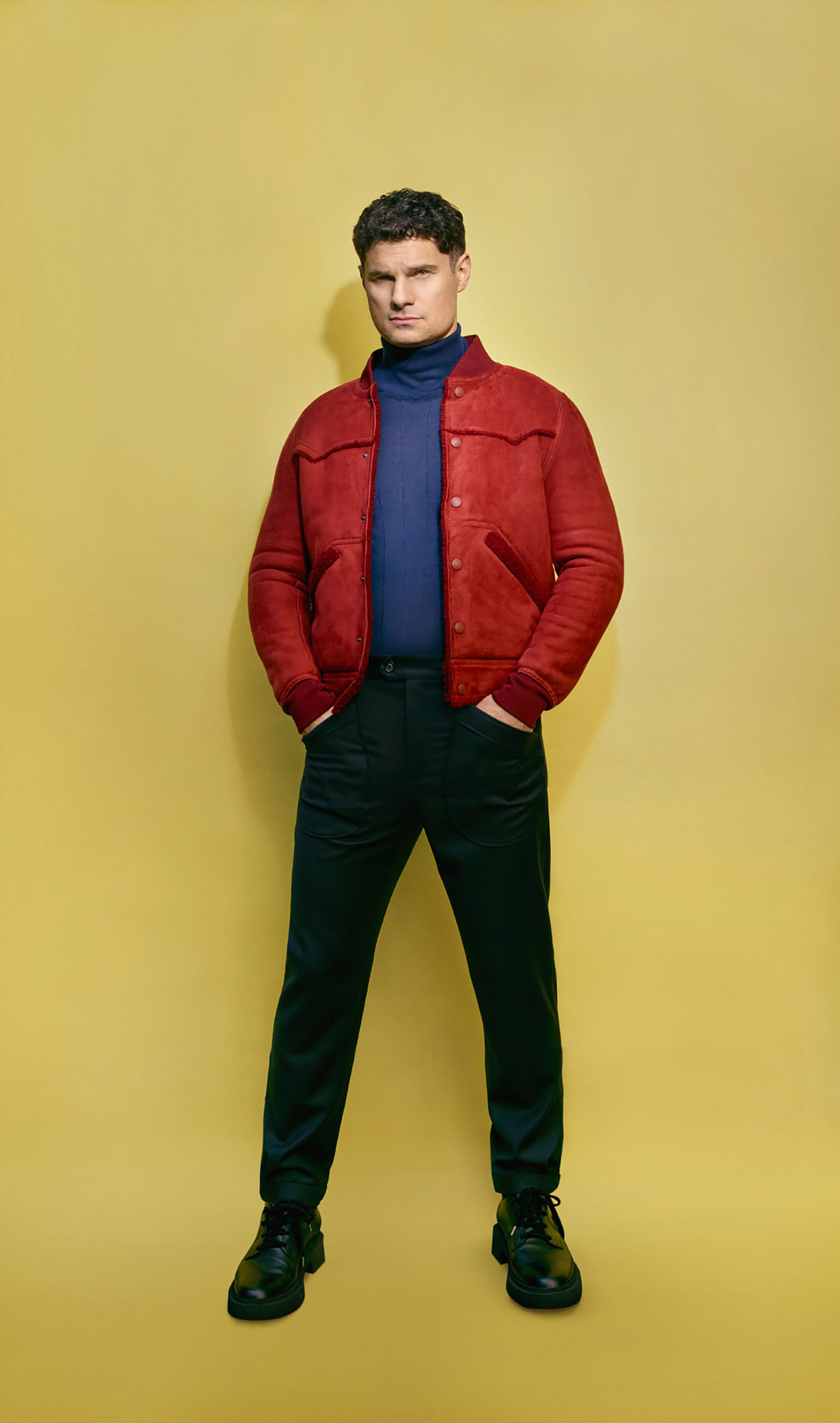 Javelin actor Flula Borg stands in front of a yellow background
